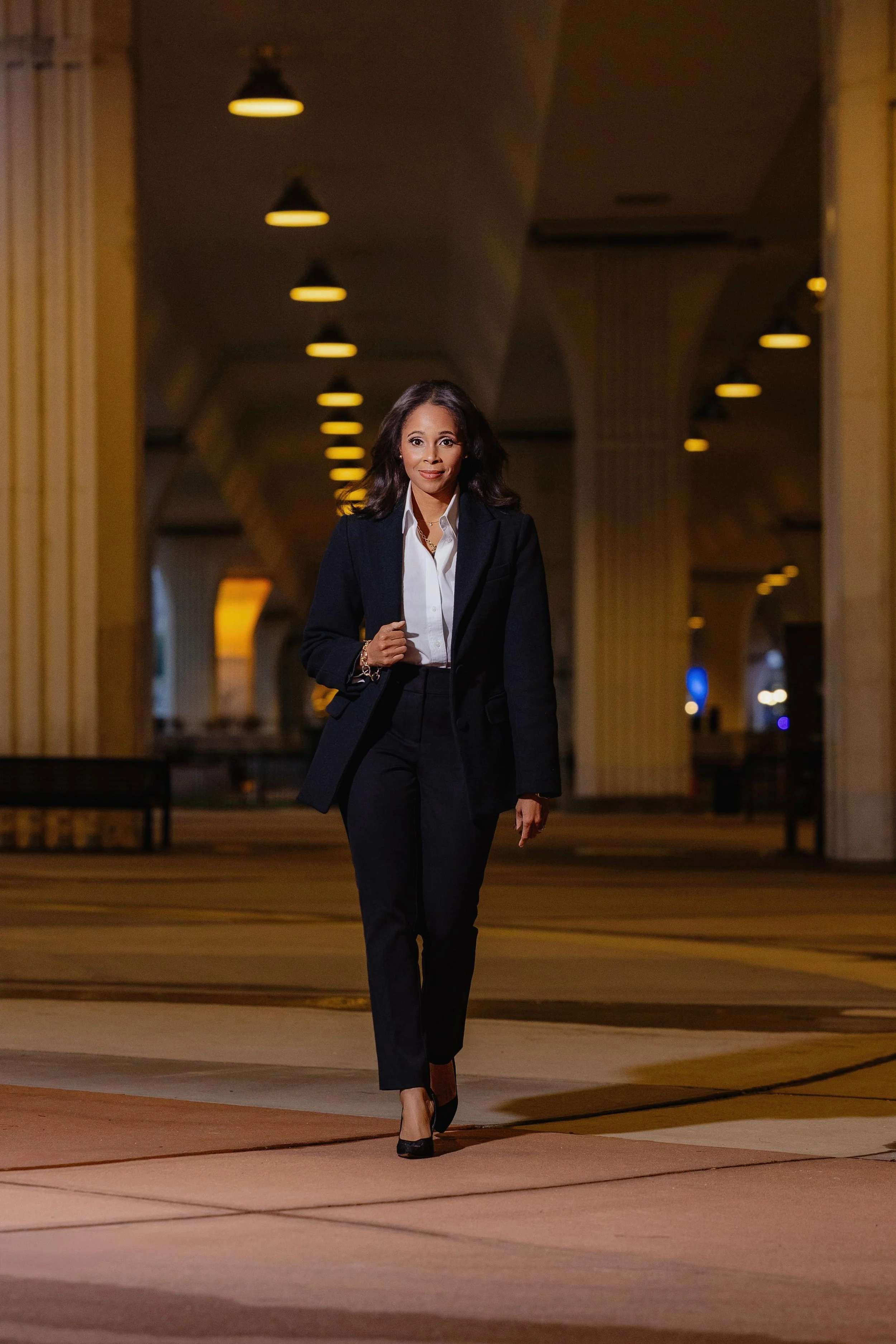 Melanie Bridgeforth, founder of Bridgeforth, walking confidently through a columned building in a dark suit
