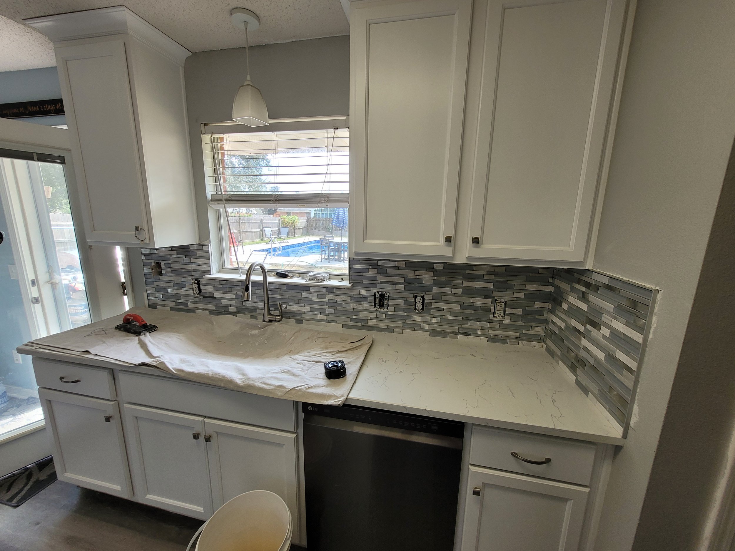 Kitchen with white cabinets, mosaic tile backsplash