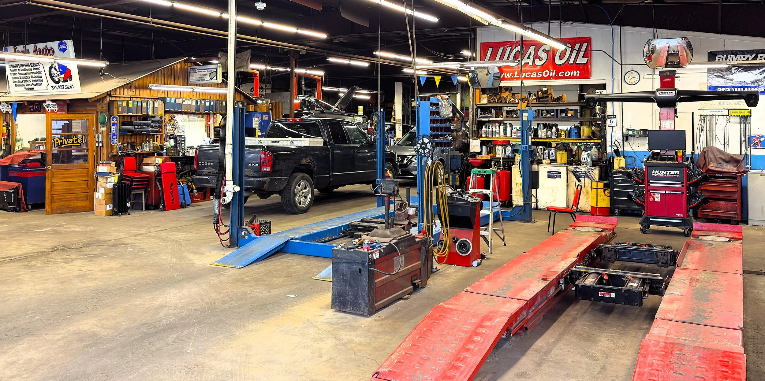 Inside an auto repair shop with vehicles on lifts, various tools, and equipment for car maintenance and repairs.