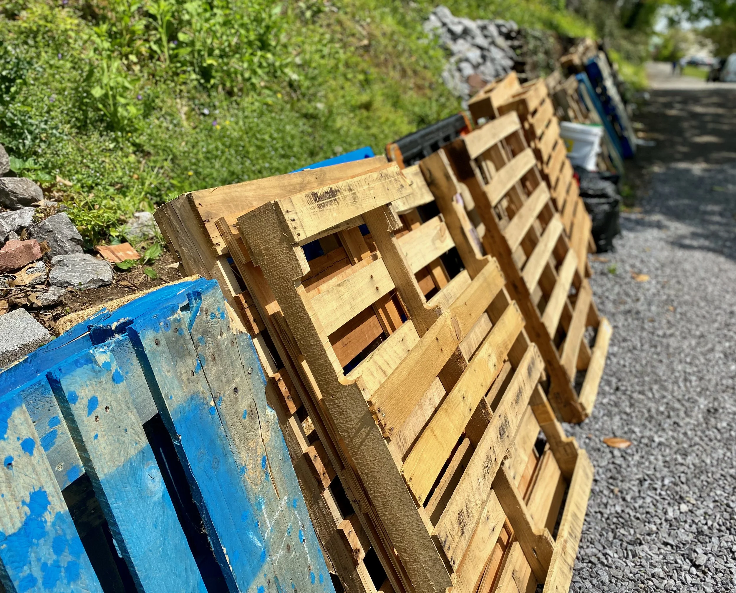 Used wooden pallets stacked against a grassy knoll