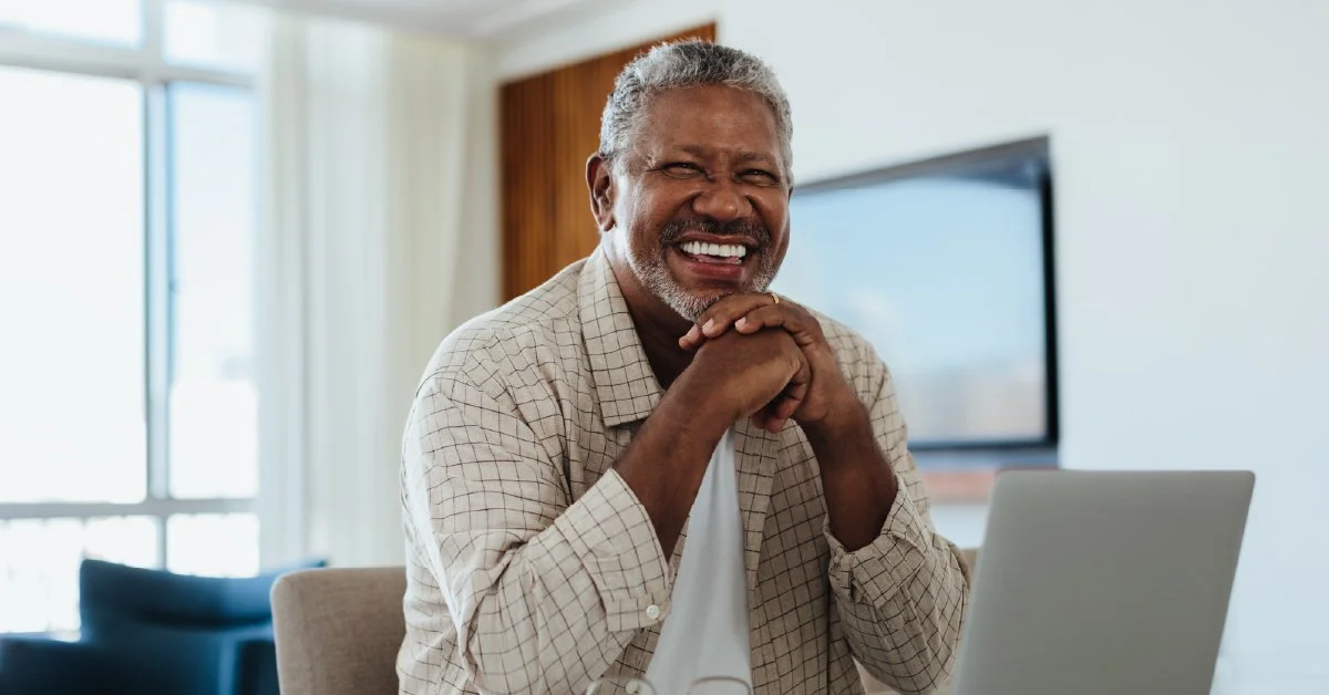 A cheerful older man with gray hair and a beard smiling.