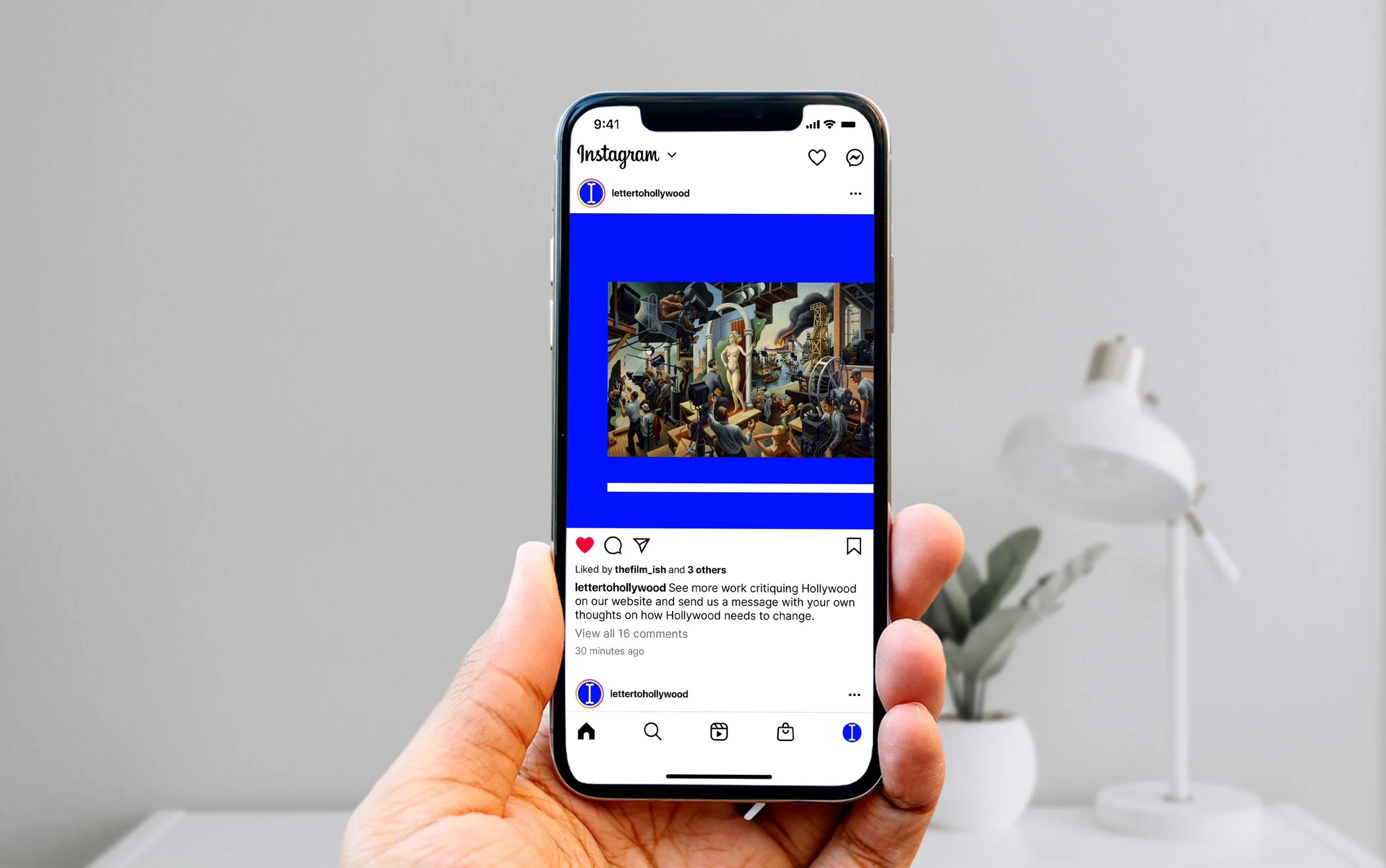 A person holding an iPhone displaying an Instagram post featuring a colorful artwork.