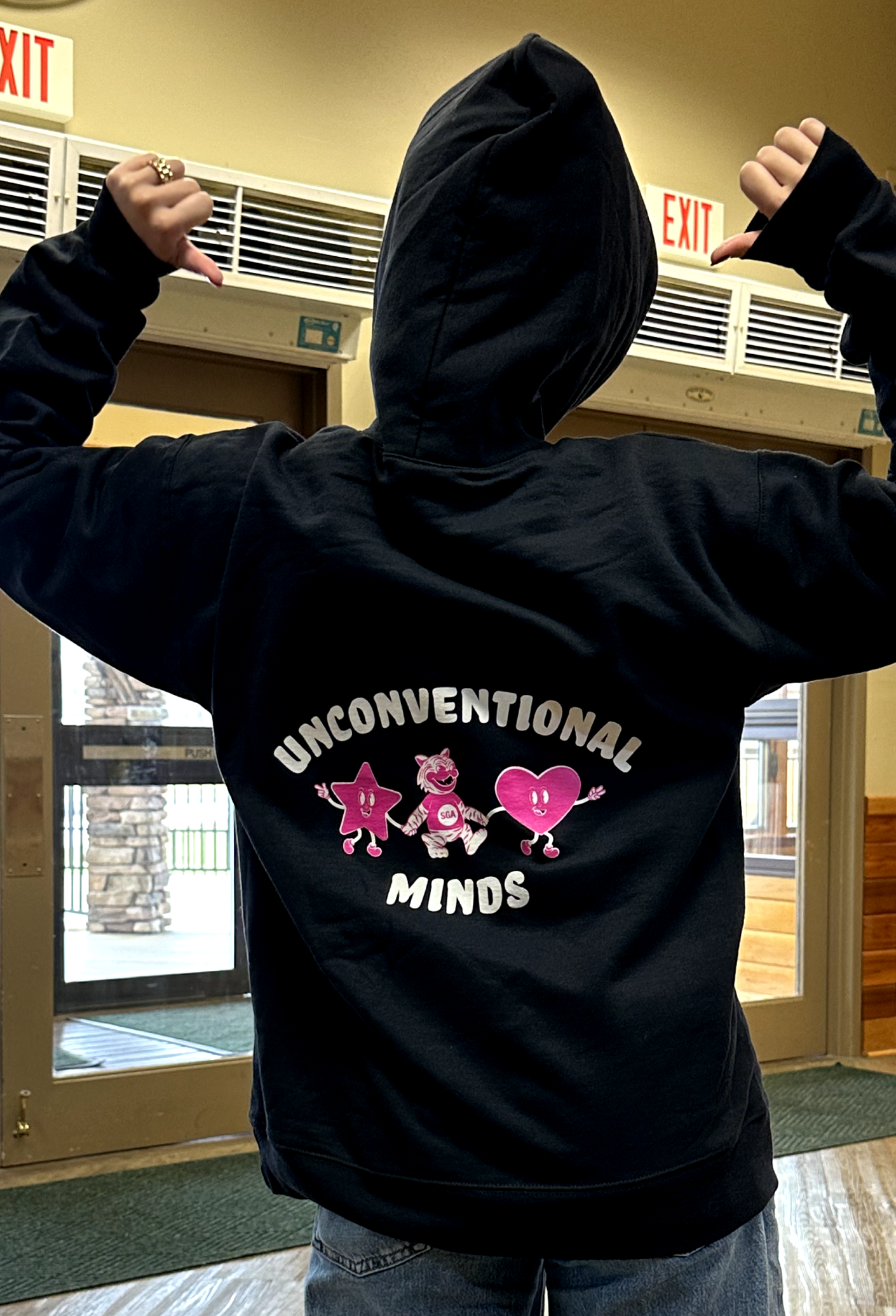 Person wearing a black hoodie with the words 'UNCONVENTIONAL MINDS' on the back.
