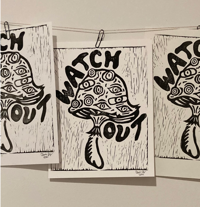 Black and white artwork with a mushroom that has eyes and spirals on it, surrounded by the words "WATCH OUT."