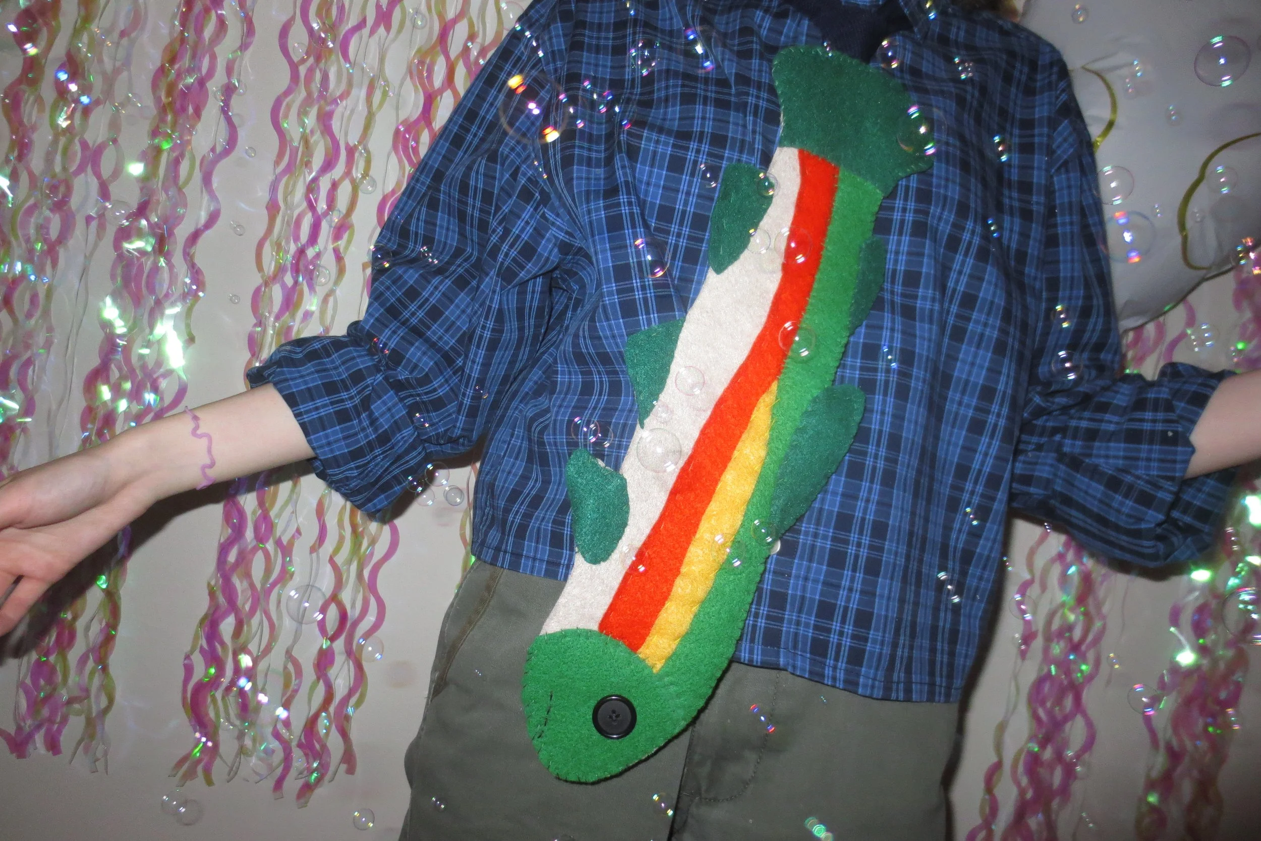 Person wearing a blue plaid shirt and a felt rainbow trout tie.