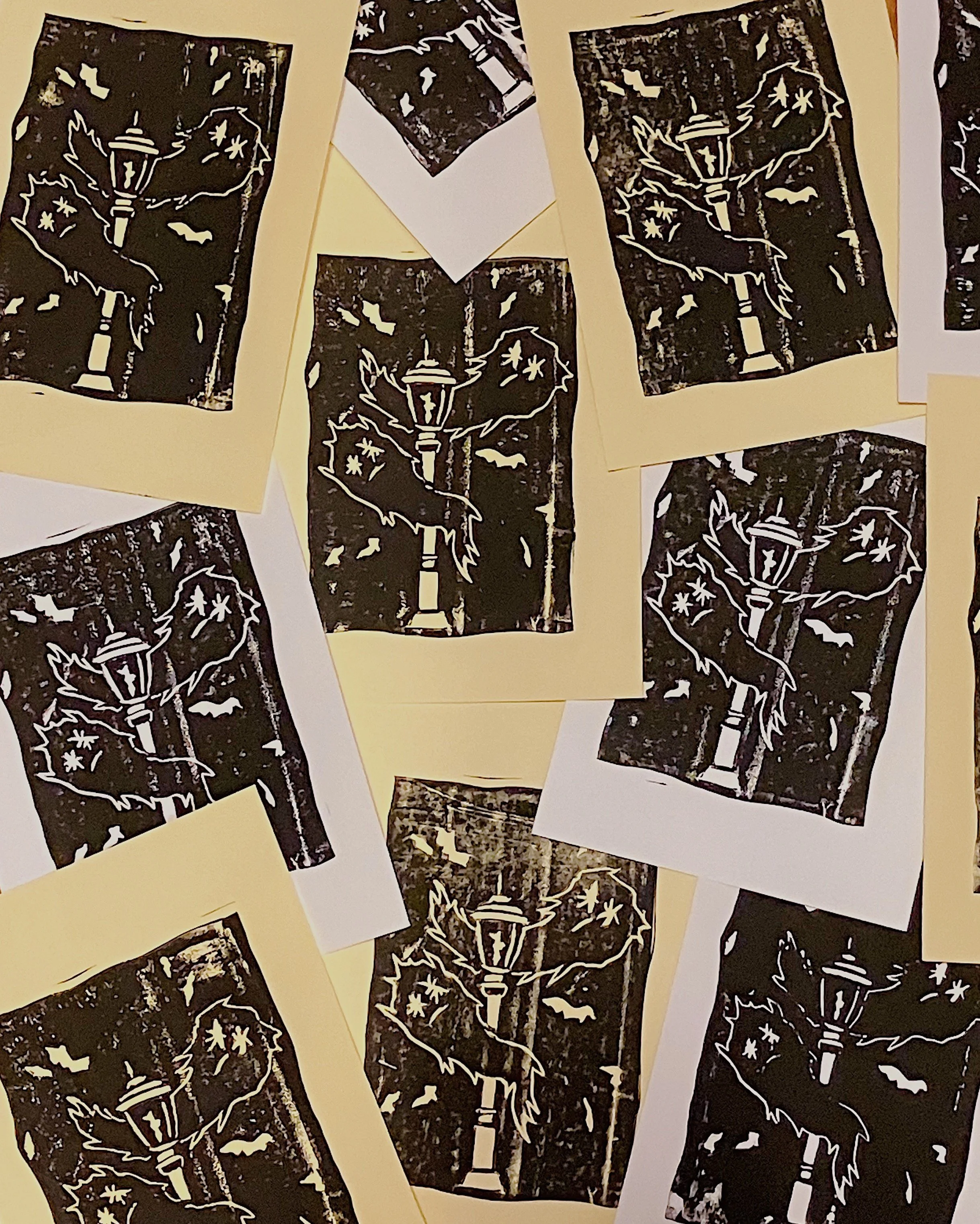Multiple sheets of paper with black and white illustrations of street lamps and ghosts overlapping each other.