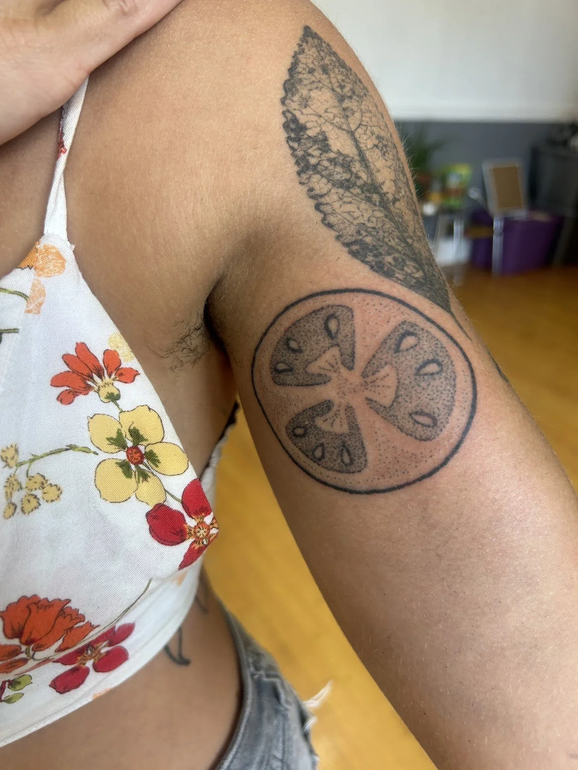 Tattoo of a tomato slice on the upper arm.