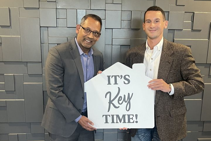 Atlanta real estate agent Cameran Jaques celebrating a home closing with a client holding an “It’s Key Time” sign