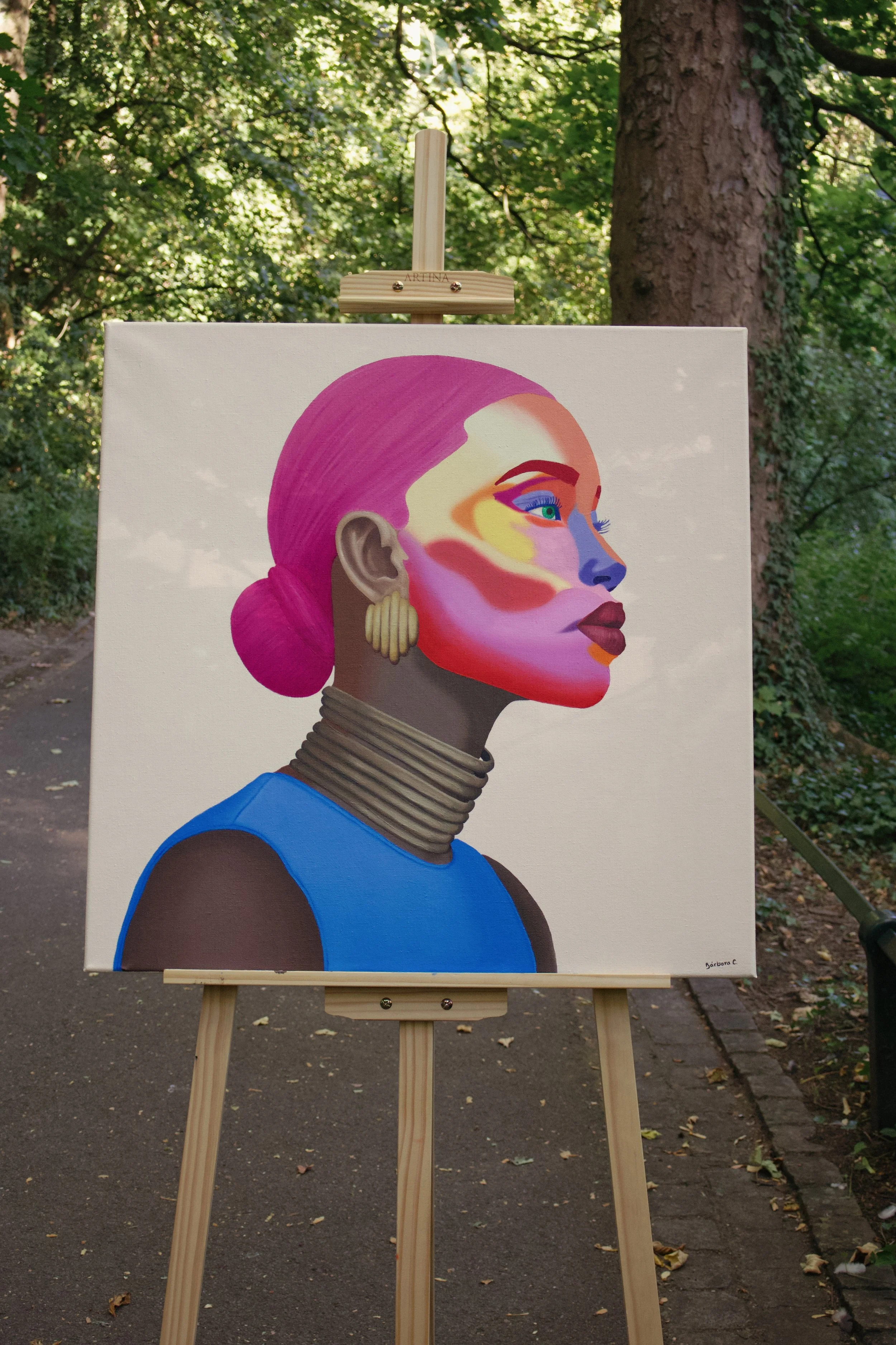 An artistic portrait of a woman with pink hair, vibrant makeup, gold earrings, multiple neck rings, and wearing a blue top.