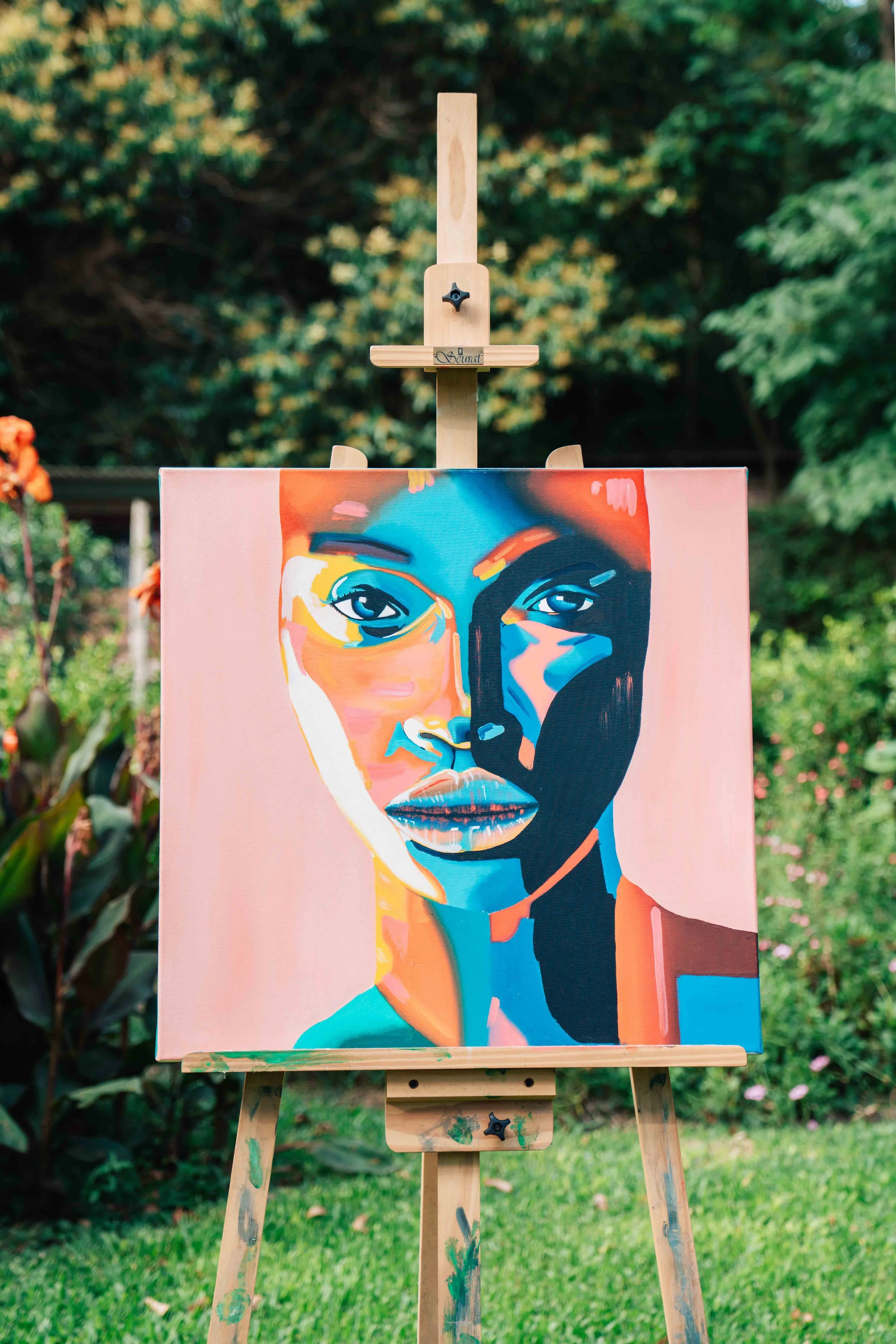 Colorful abstract portrait of a woman with a serious expression, painted on canvas and displayed outdoors on a wooden easel with a lush green background.