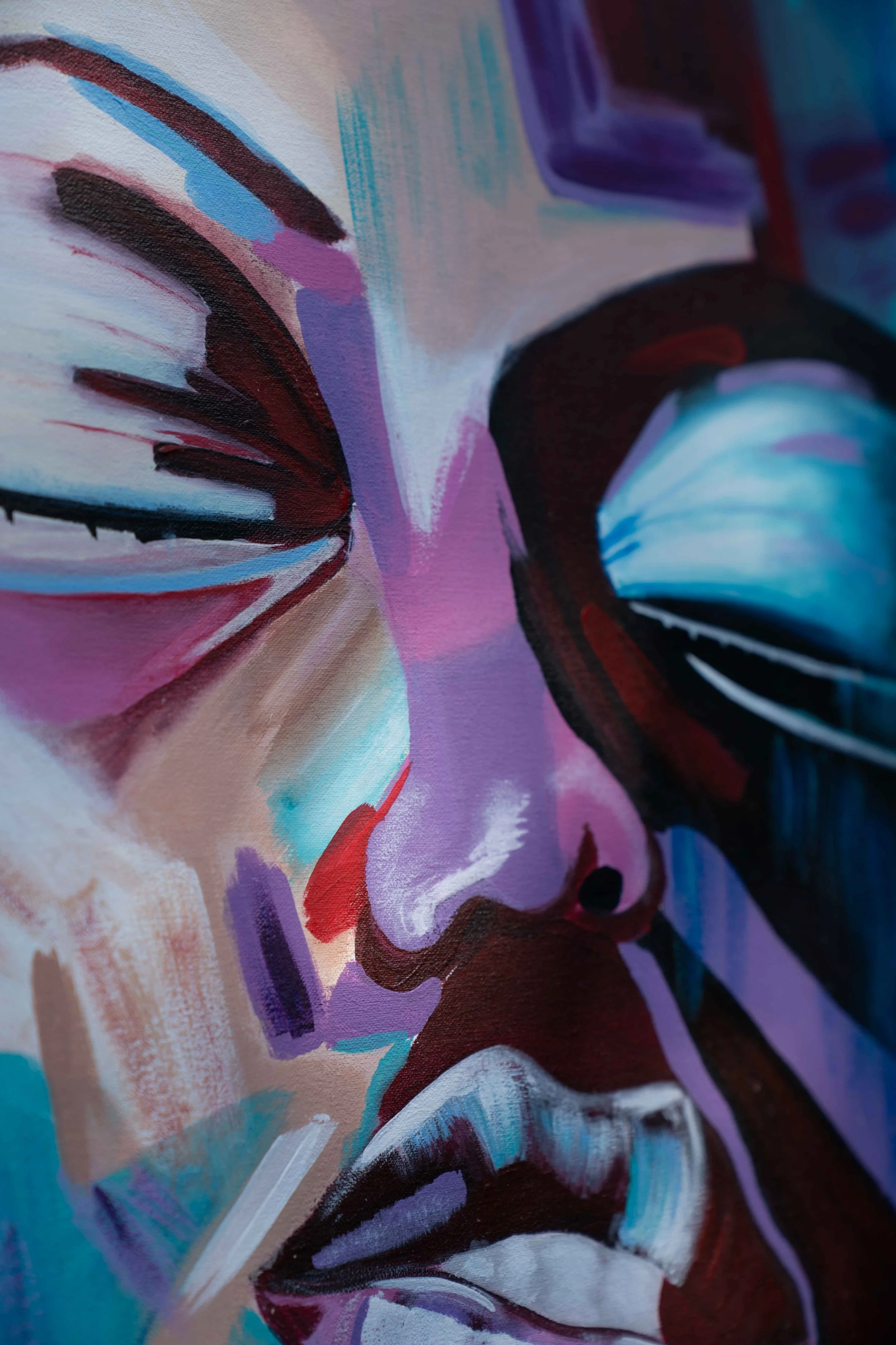 Close-up of an abstract painting with vibrant colors, including shades of purple, blue, red, pink, and black, with sweeping brushstrokes and fluid forms.