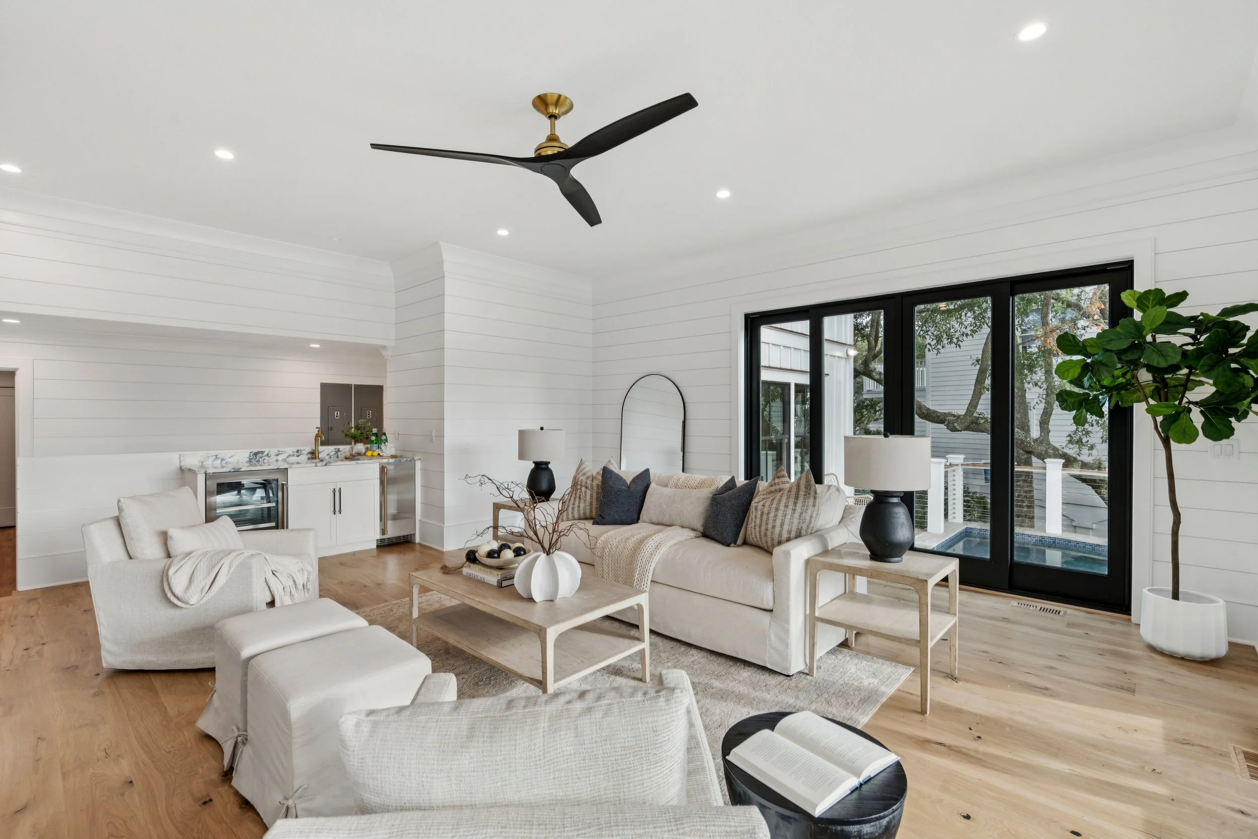 Living room with white walls, large windows, furniture, and decorative items.