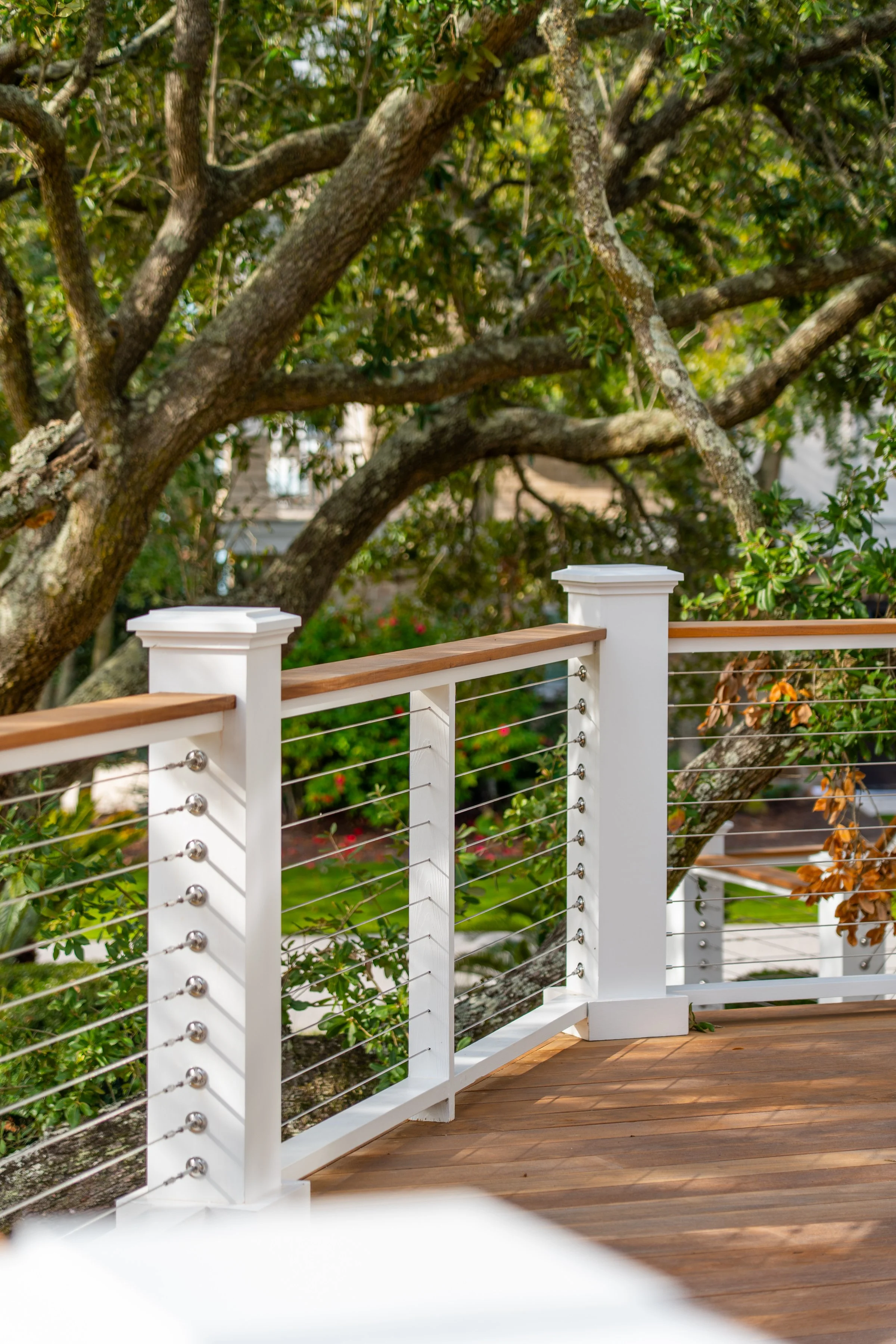 A wooden deck with a white railing overlooking green trees and foliage.