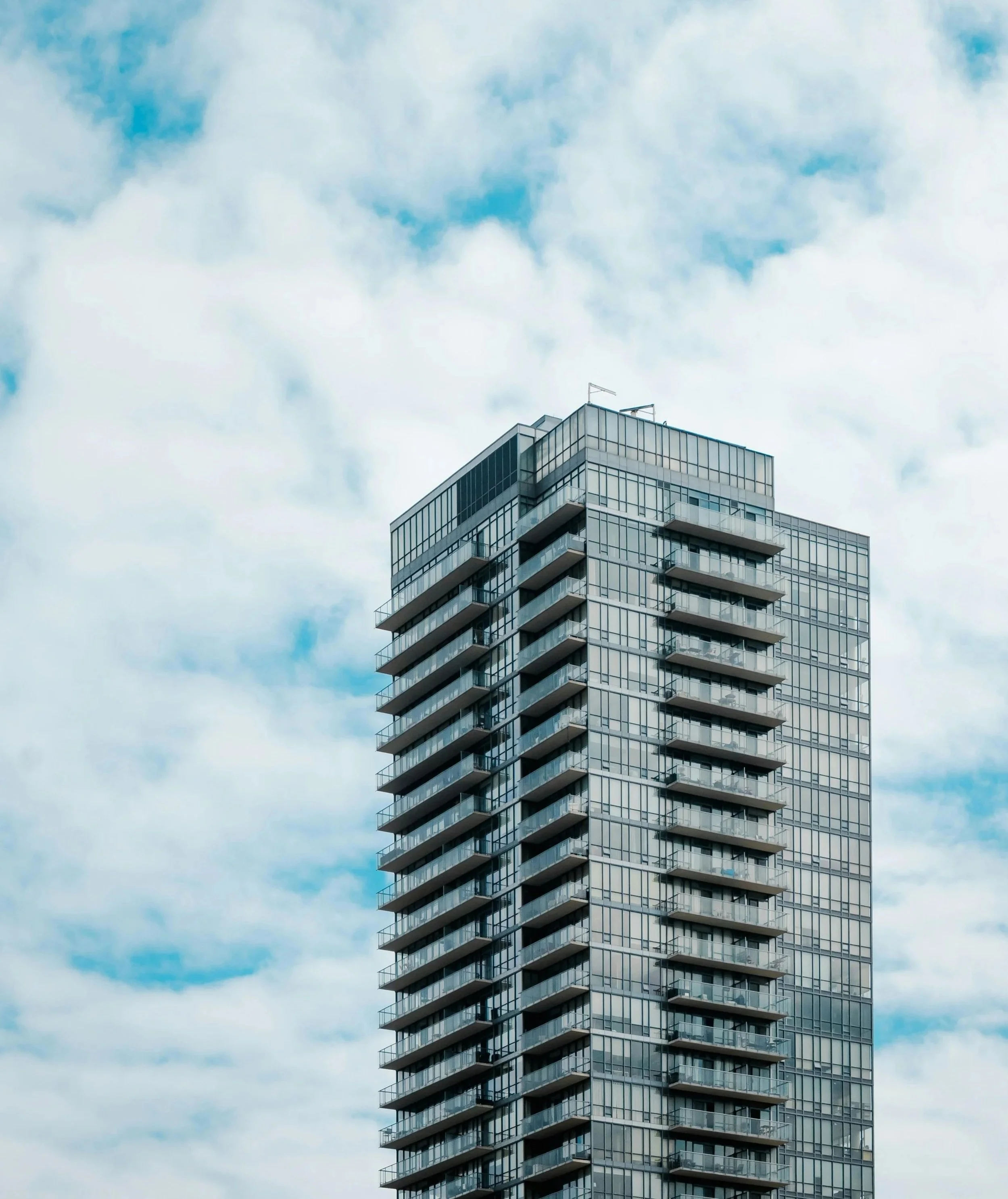 Condo with blue sky and clouds reflecting off the glass of the building.jpg