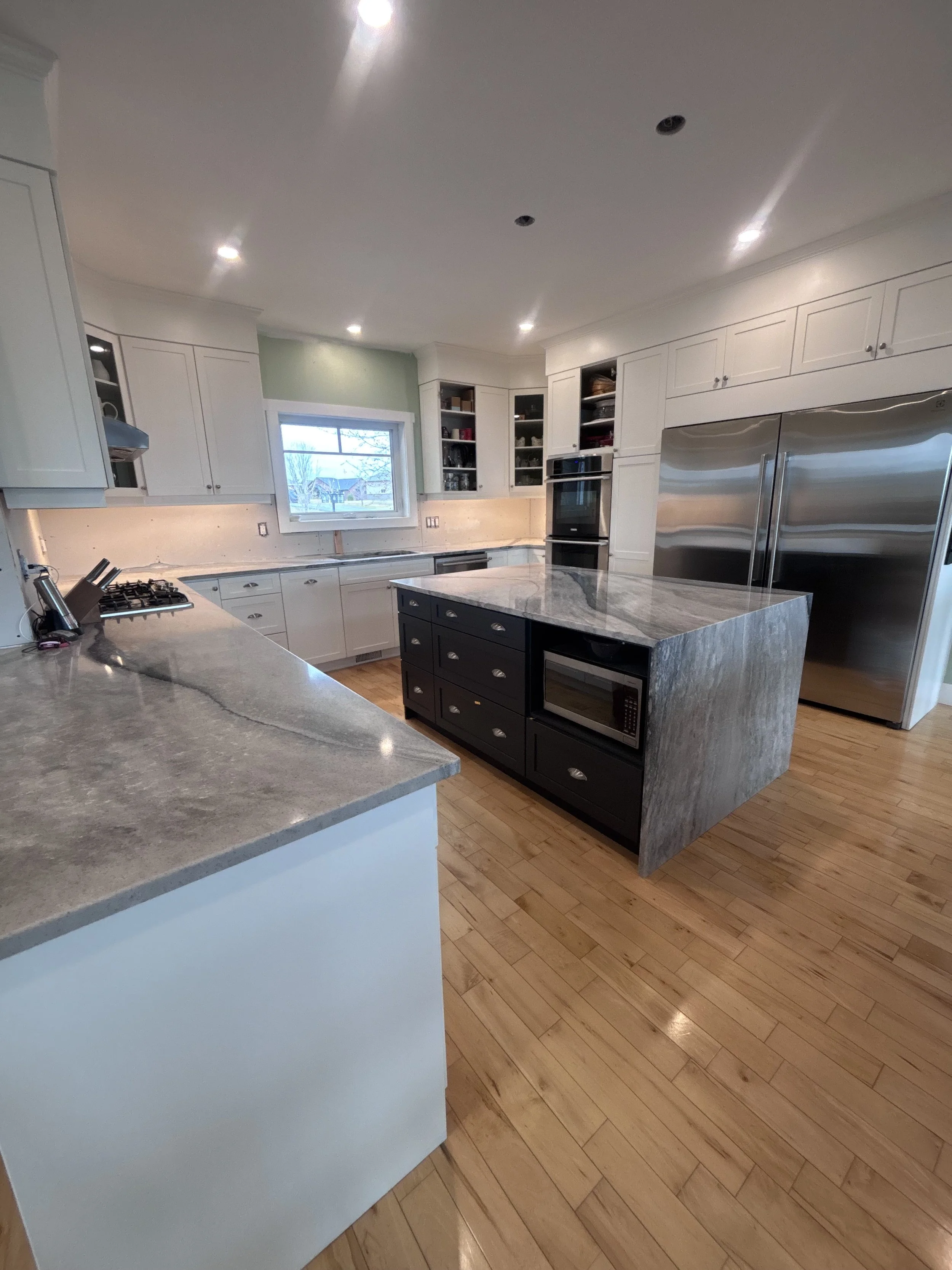 Open-concept kitchen renovation with white cabinets, granite countertops, custom island, and hardwood floors
