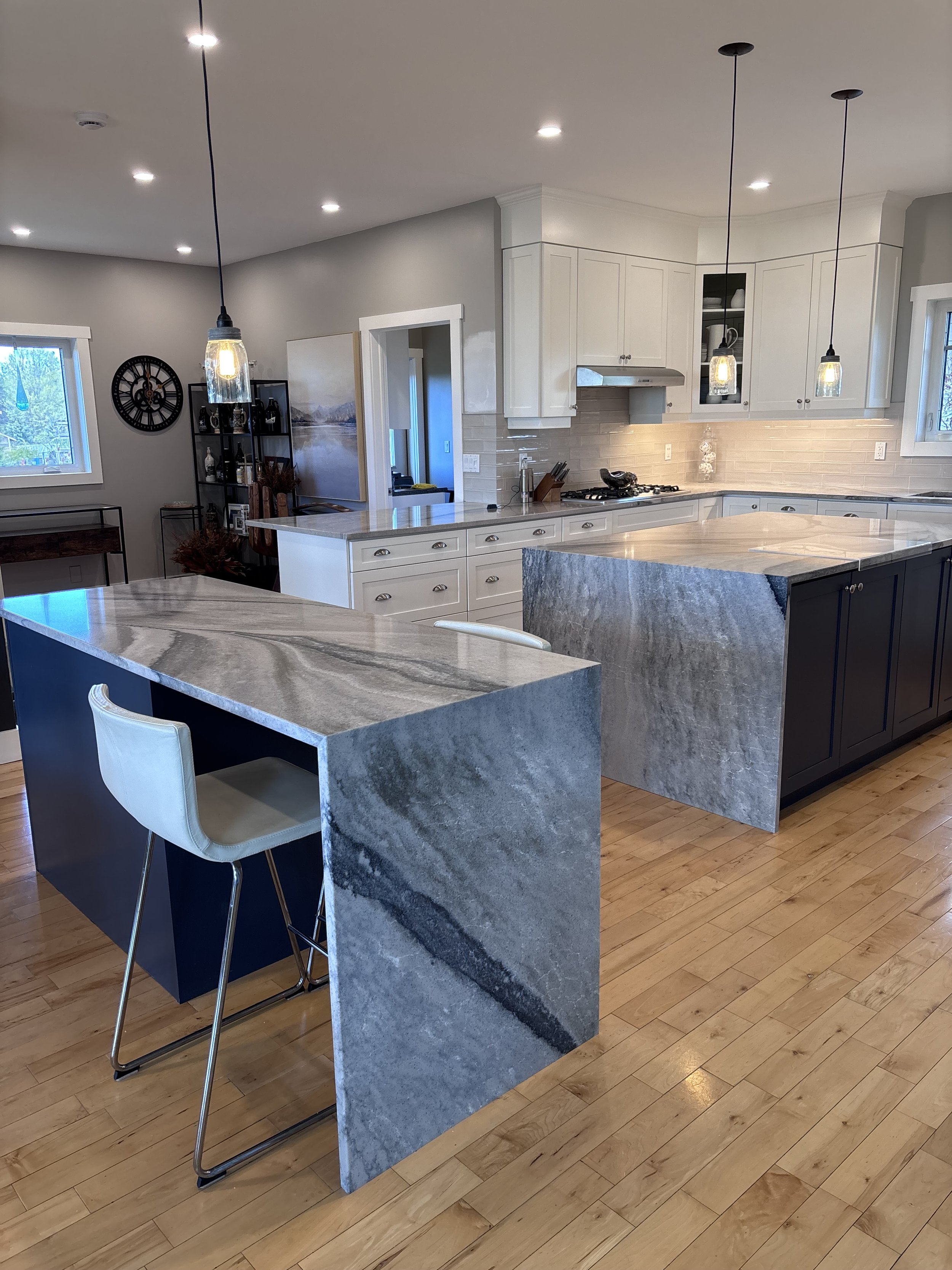 Modern kitchen renovation with white cabinetry, granite countertops, pendant lighting, and hardwood flooring. In Uxbridge, Ontario