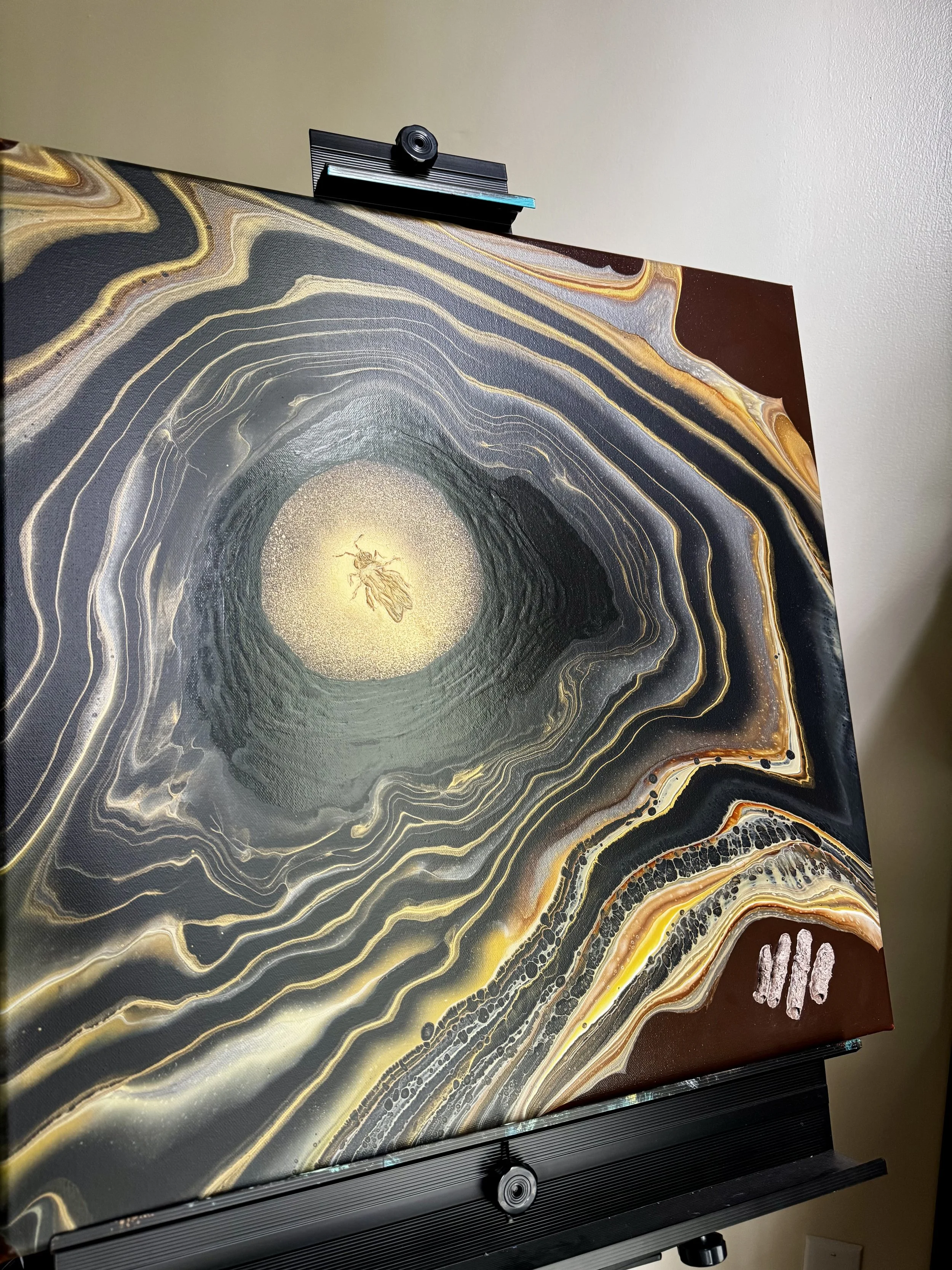 Painting of a chimney bee with fluid art elements in gold, yellow, black, and brown, and textured paste representing turret structures.