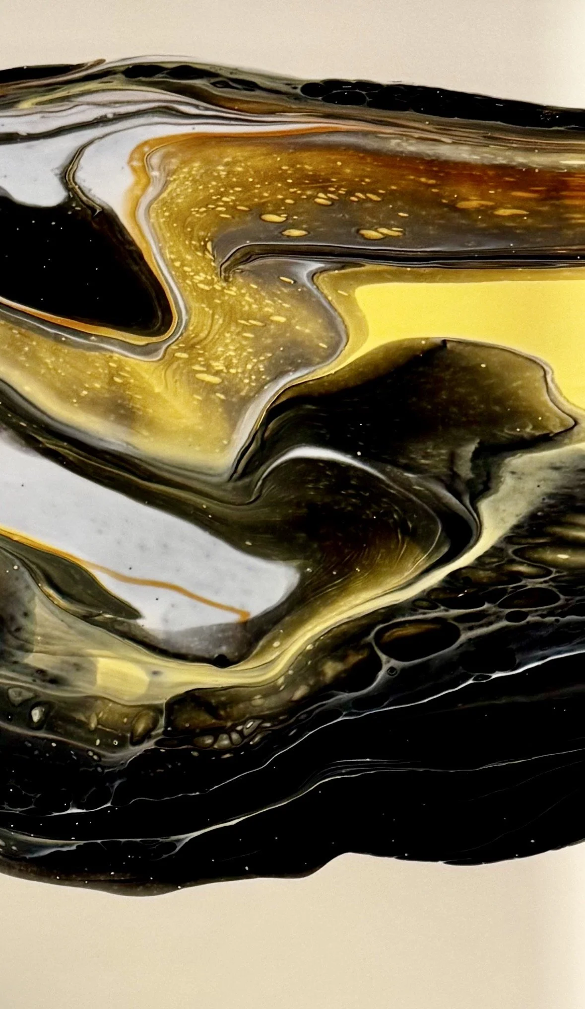A fluid art painting with gold, black, white, and yellow paint.