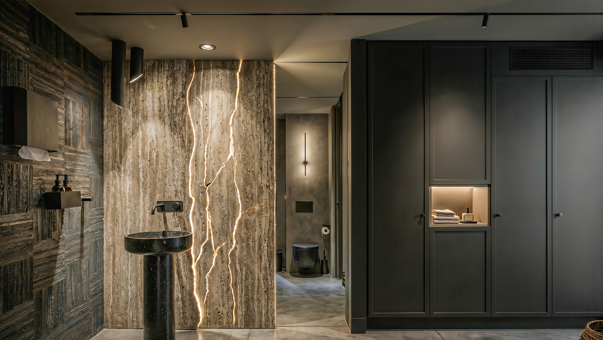 Modern bathroom with dark cabinetry, a black toilet, a black sink with a gold faucet, and unique backlit cracked wall design.