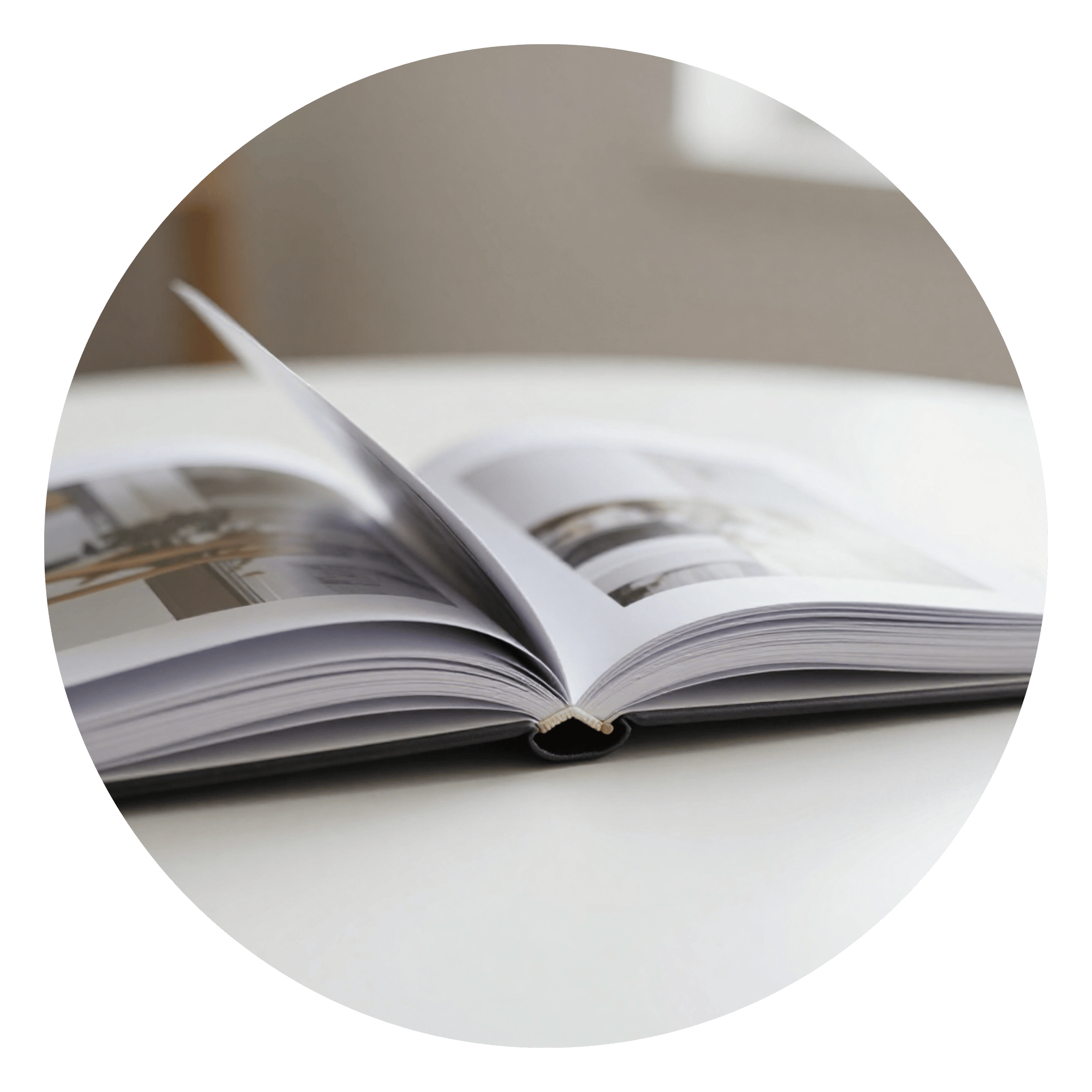 An open magazine with pages displayed on a white table.