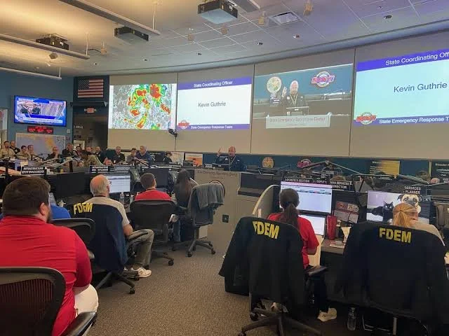 Emergency operations center with large video wall displays and staffed workstations