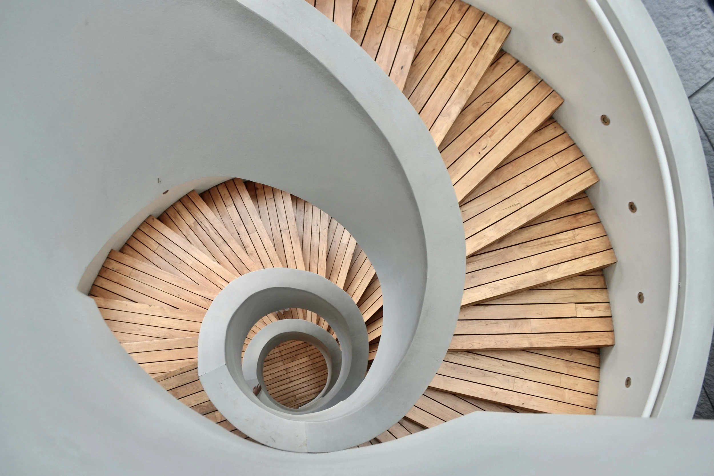 Top-down view of a spiral staircase with wooden steps and white railings.