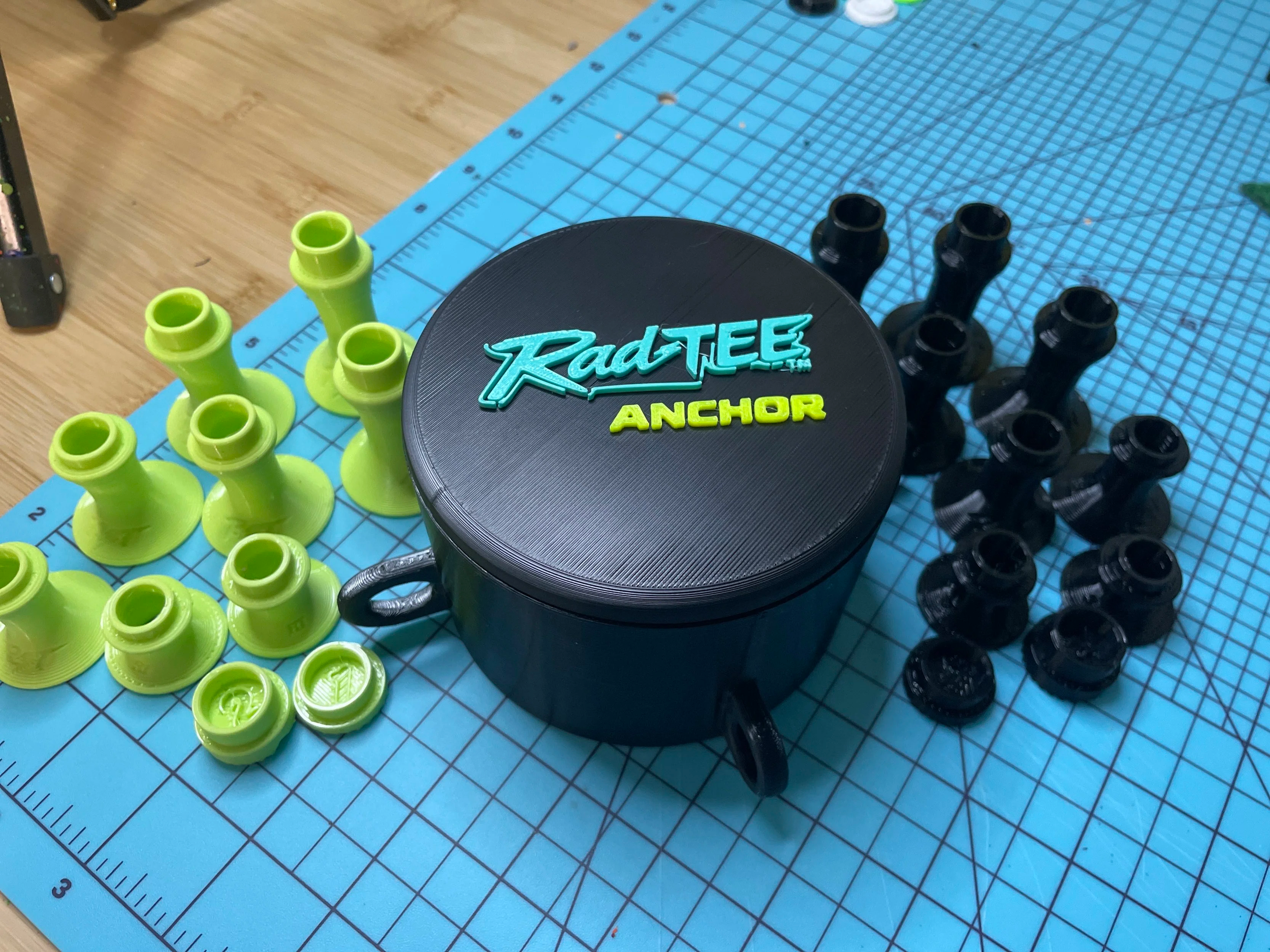 Green and black plastic objects arranged on a blue cutting mat with measurement markings.