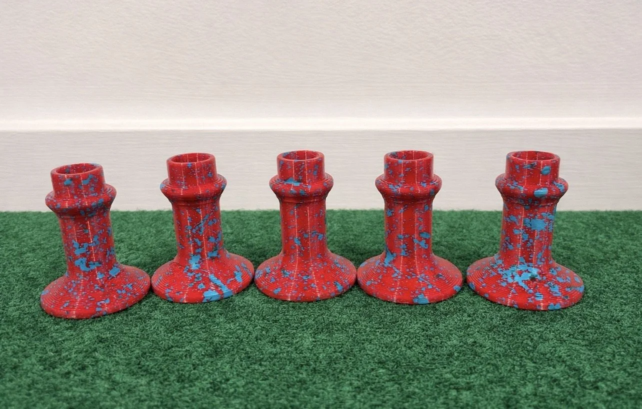 Five red and blue speckled chess rooks lined up on green felt.