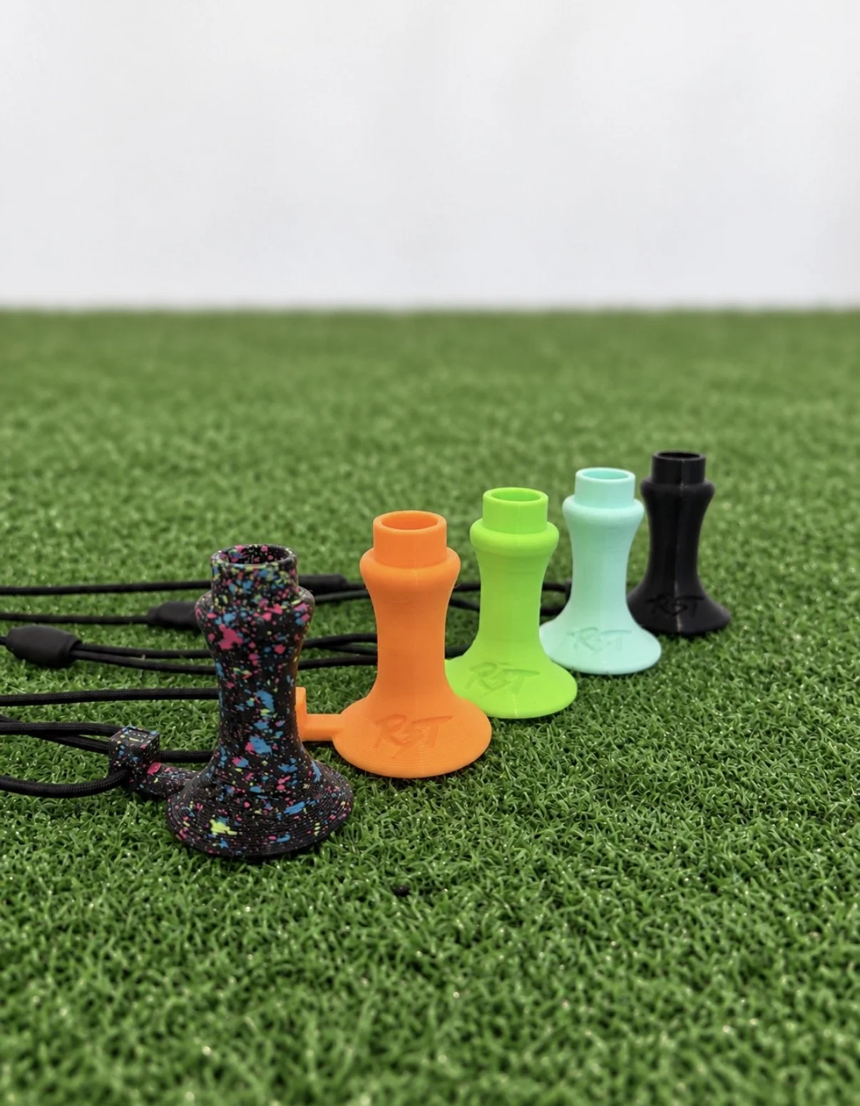 A set of colorful silicone shoelace clips with ropes attached, arranged on a green artificial grass surface.