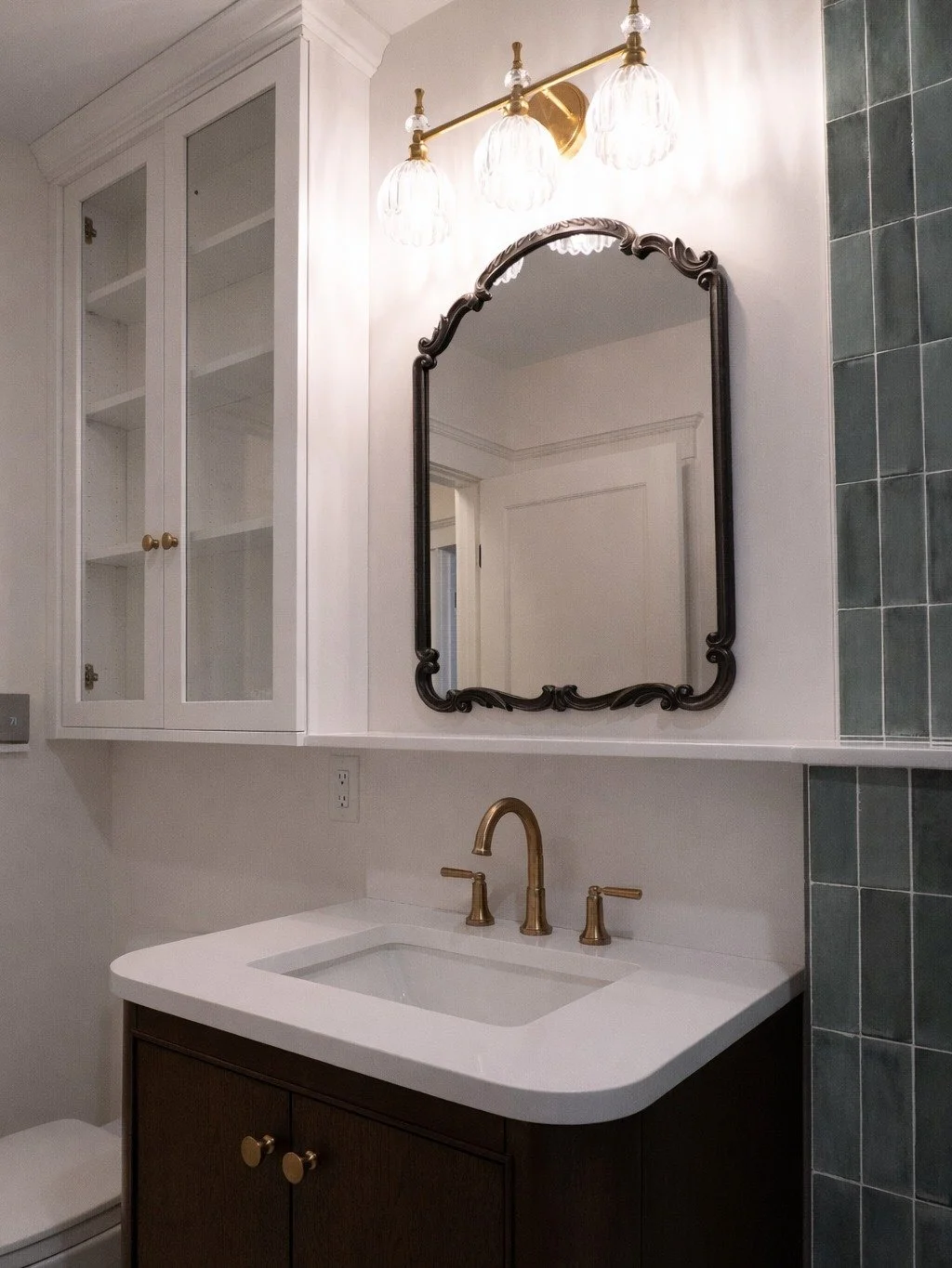 We carried the same color palette from the kitchen into this West Roxbury bath. Warm brass, rich wood tones, and soft whites, so the spaces flow naturally into each other. It creates consistency without feeling matchy, and makes the whole house feel 