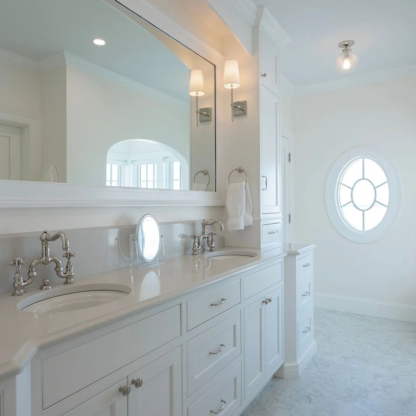 This primary bath was designed to feel timeless from day one. Custom inset cabinetry, polished nickel fixtures, layered millwork, and a soft marble floor that reflects natural light from the oval window. Every line is intentional. Every detail is ali