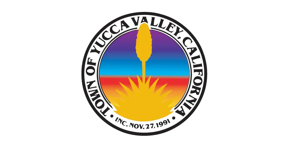 The logo of the Town of Yucca Valley, California, featuring a colorful circular design with a yellow cactus silhouette and a sunset background, including text with the town's name, state abbreviation, and founding date.