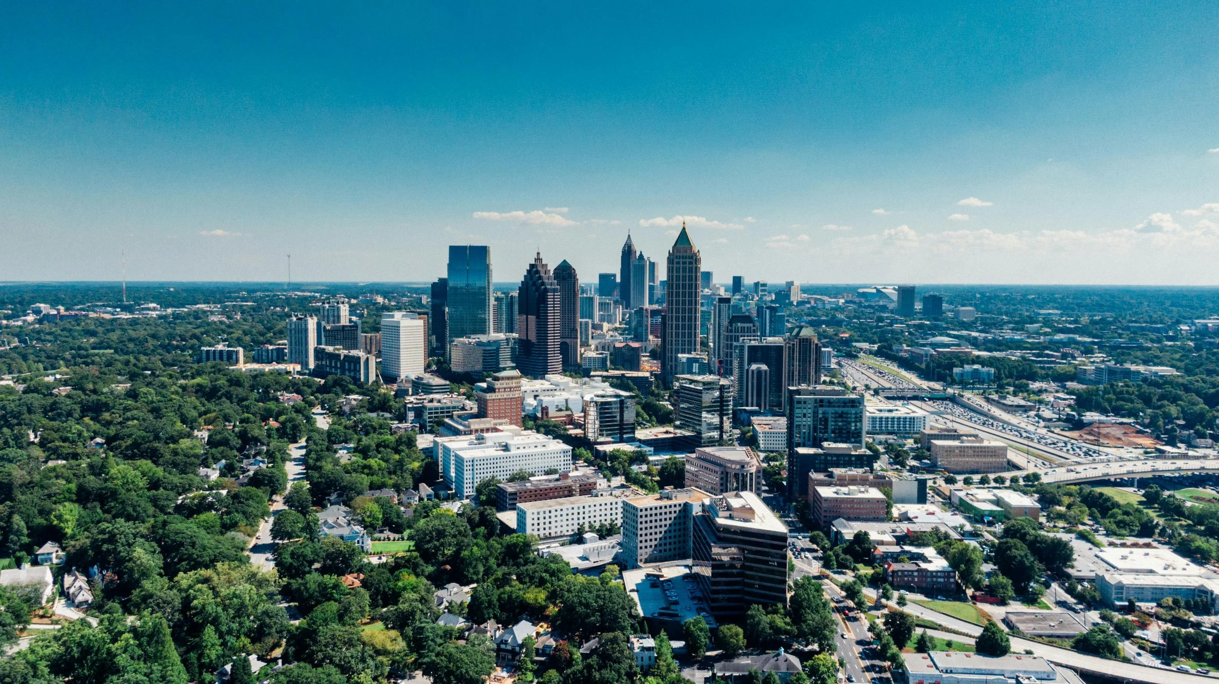 Atlanta skyline with green trees in the foreground, marking the location of Healthy Mind, Healthy Heart's therapy office at Riverwood Parkway