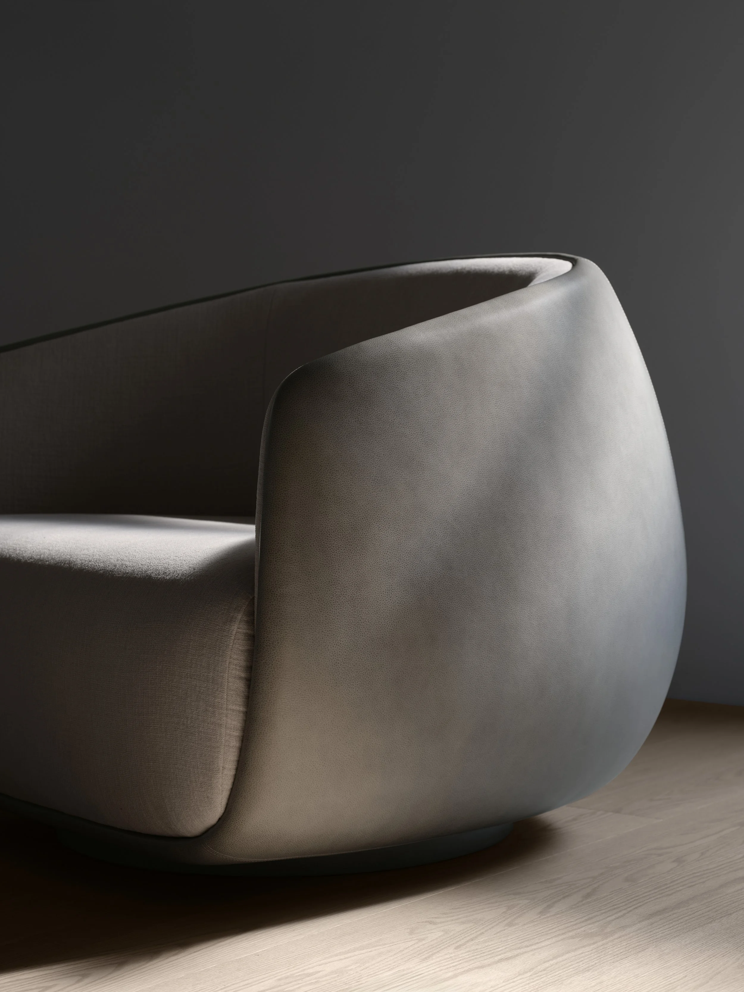 Close-up of a modern, light gray upholstered armchair with curved design, placed on a wooden floor against a dark gray background.