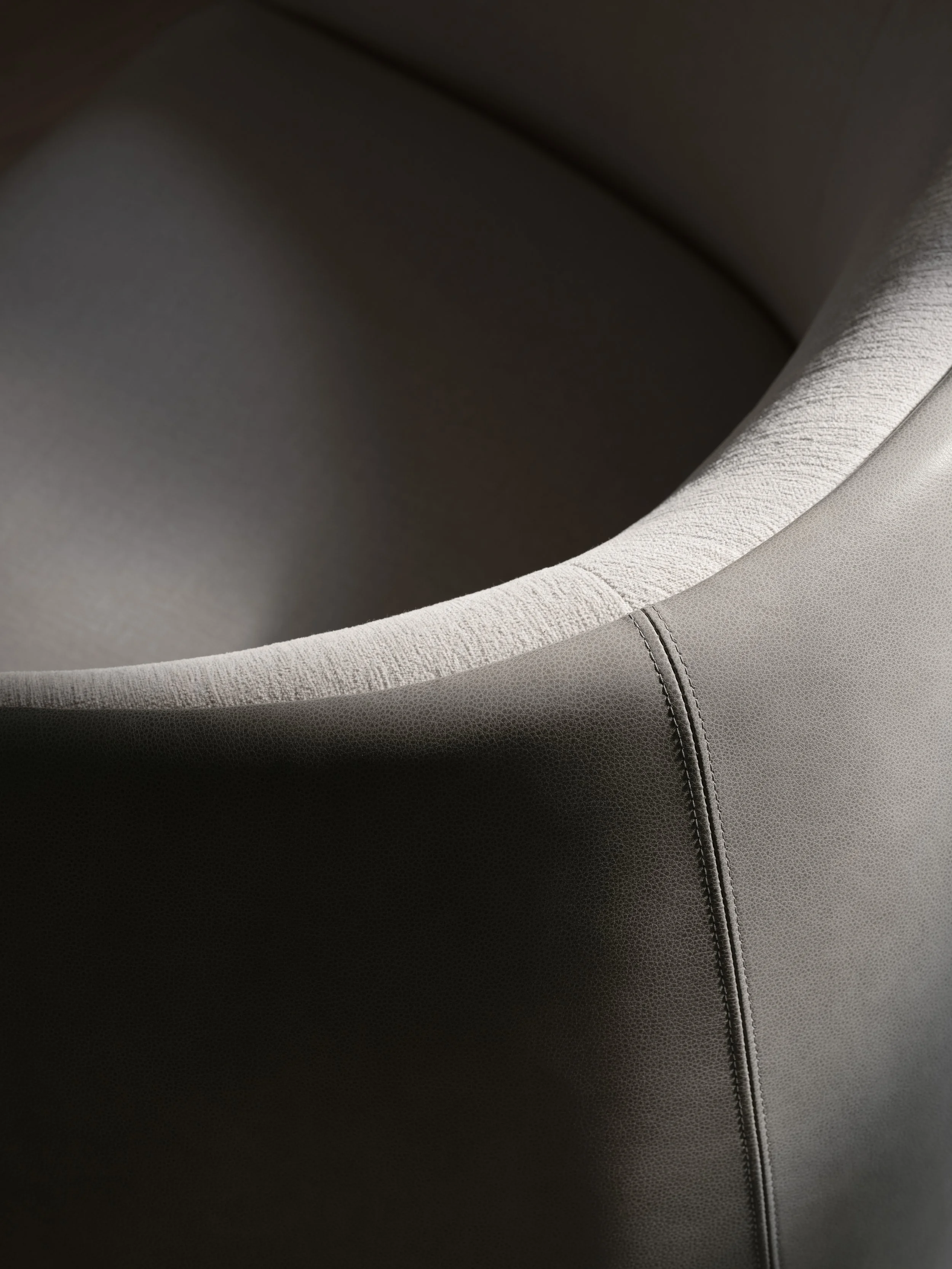 Close-up of a circular, padded, textured armrest or headrest, with stitched seams visible.