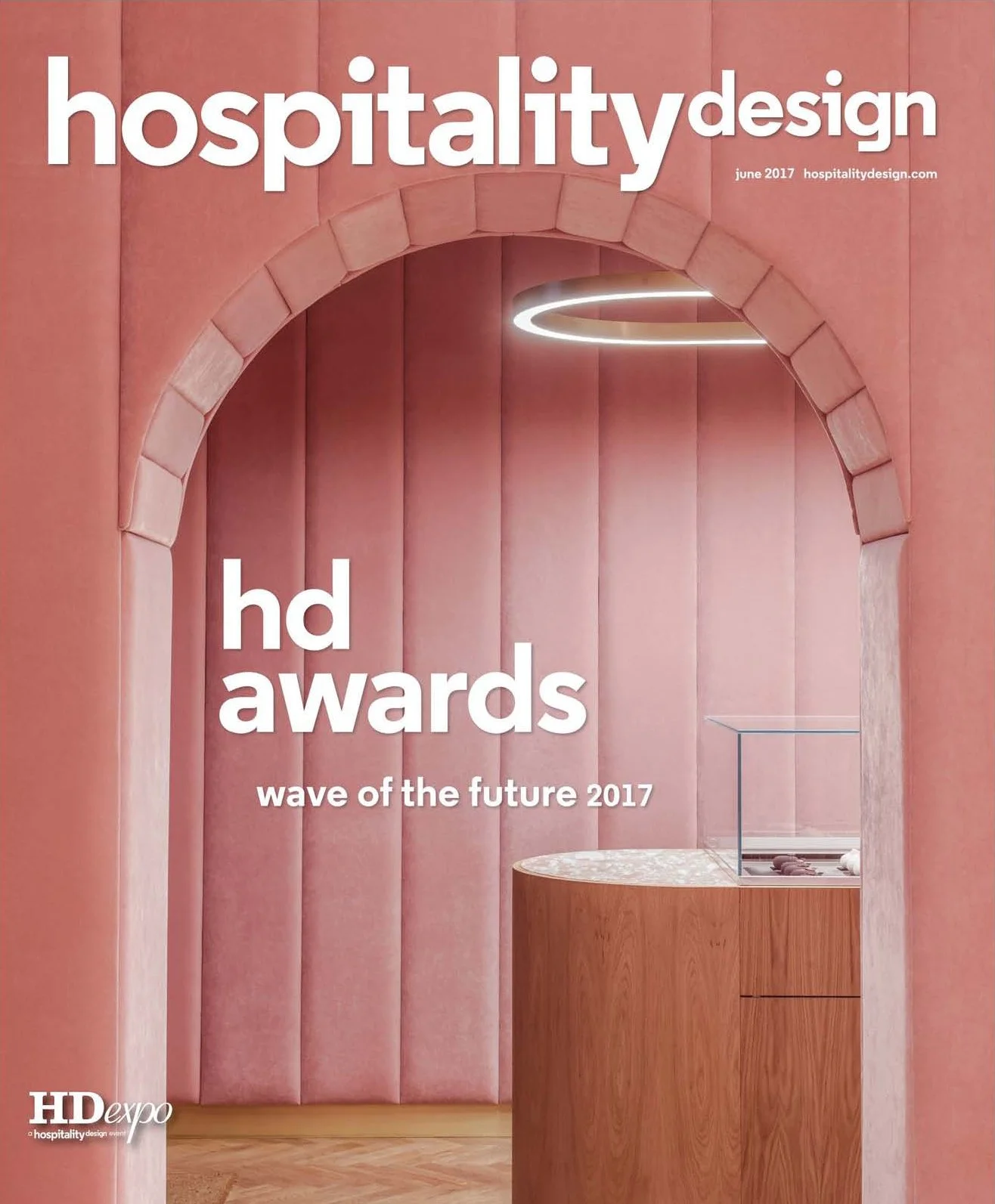 Cover of Hospitality Design magazine, June 2017, featuring interior of a modern space with pink upholstered walls, an archway, a circular ceiling light, and a wooden display table.