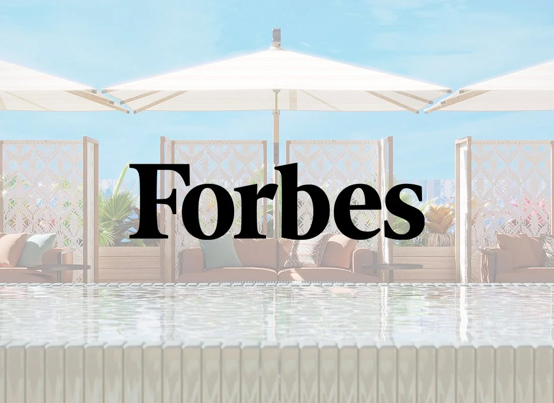 Poolside scene with white umbrellas, outdoor furniture, and lounge chairs on a sunny day.