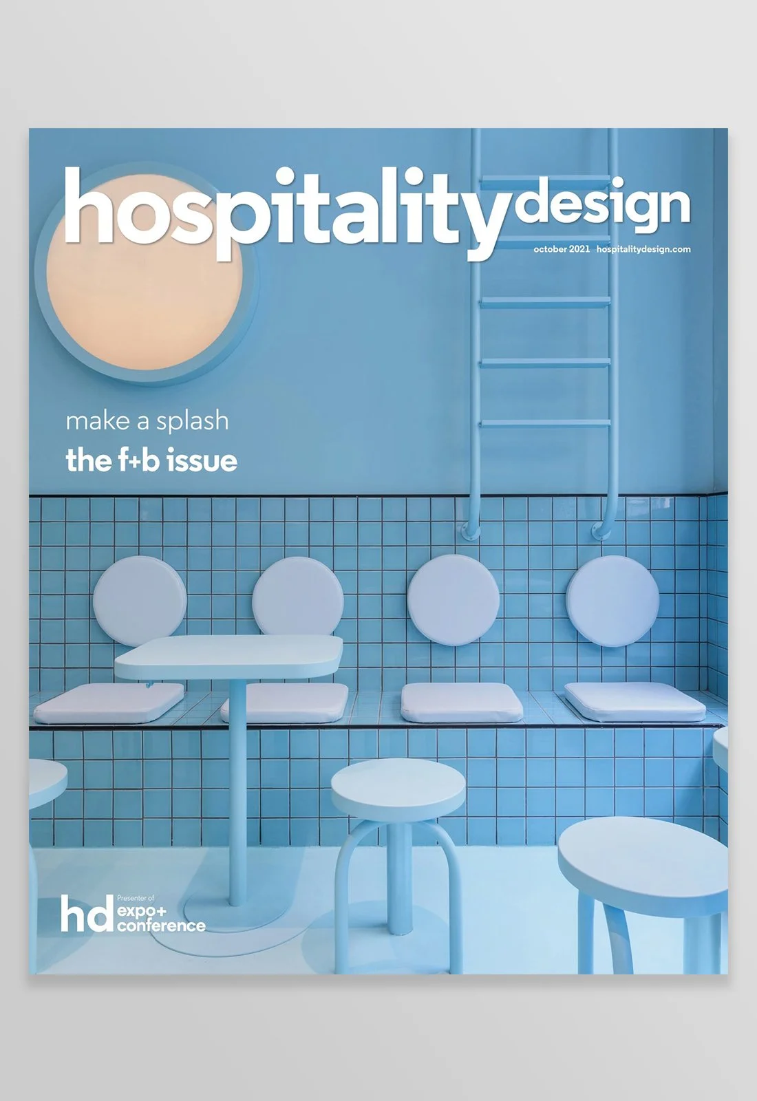 Magazine cover titled 'hospitality design' with a blue tiled room, four round chairs with cushions, a table, and a ladder on the wall.