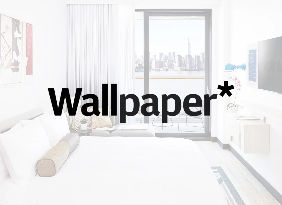 Bright, modern bedroom with a city skyline view, white bedding, wall art, a balcony with a table and chairs, and a flat-screen TV.