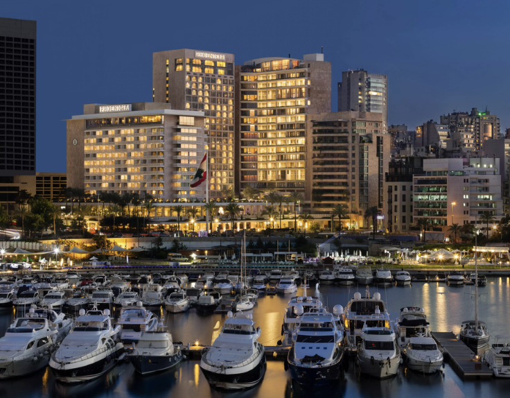 City skyline with illuminated high-rise buildings and a marina filled with yachts during evening