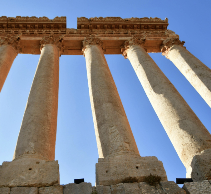 Ancient stone columns of a Greek or Roman temple against a clear blue sky.