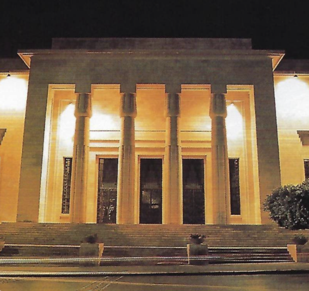 Front view of a government building with tall columns illuminated at night.