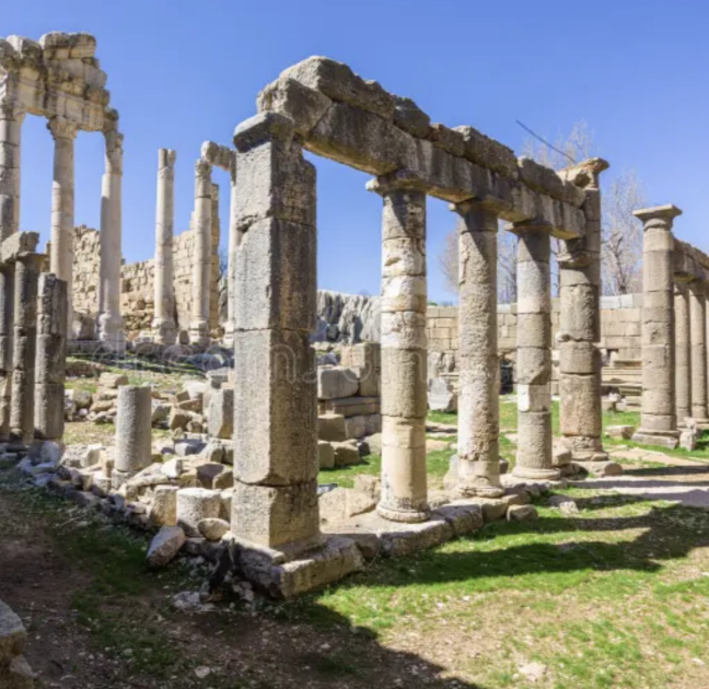Ancient ruins with stone columns and structures against a bright blue sky.