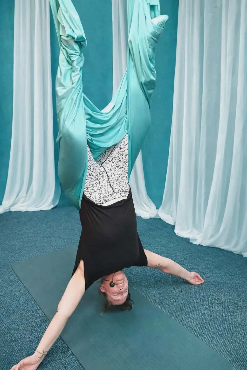 A woman doing an inversion yoga pose in an aerial yoga hammock