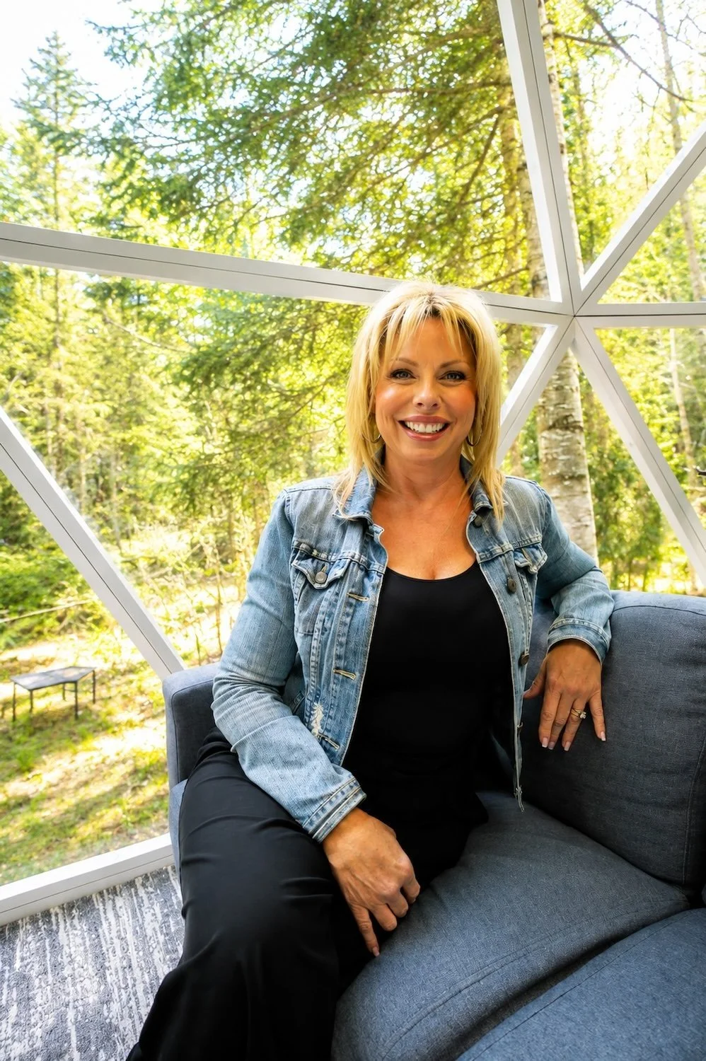 Melanie Hammond, Founder and Editor of Parallel Muskoka, seated in a geodesic dome surrounded by Muskoka forest.