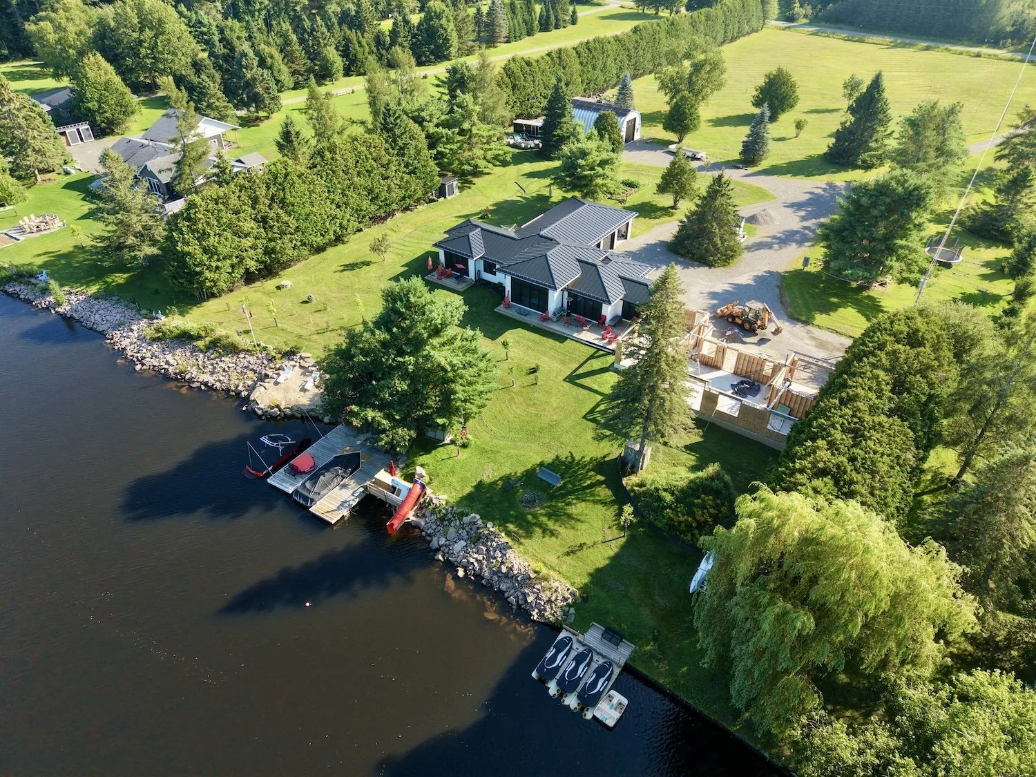 Dark standing seam steel roof with multiple gables on a waterfront Muskoka home seen from above