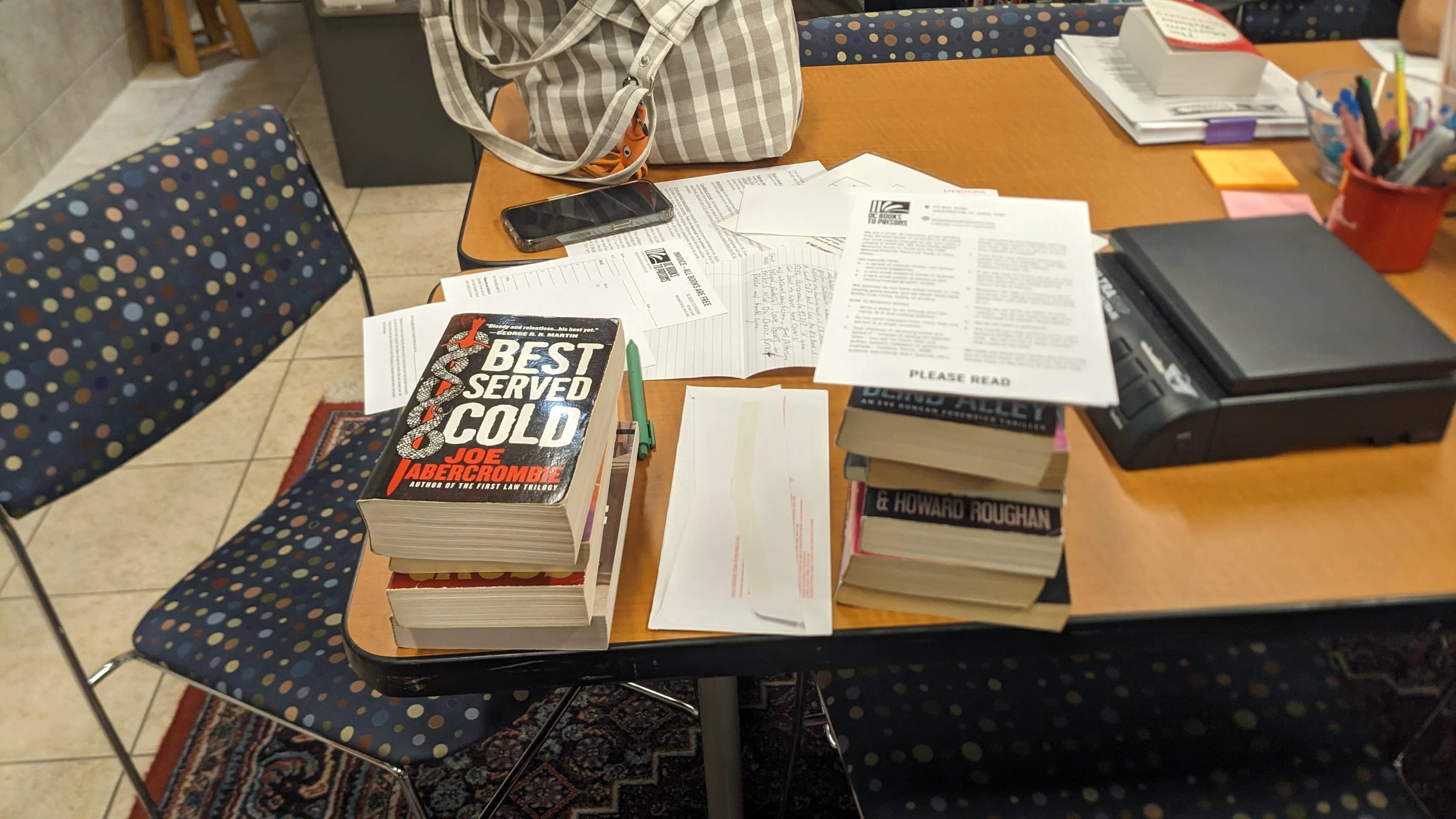 Two stacks of books with Books to Prisons stationary about to be filled out to send.