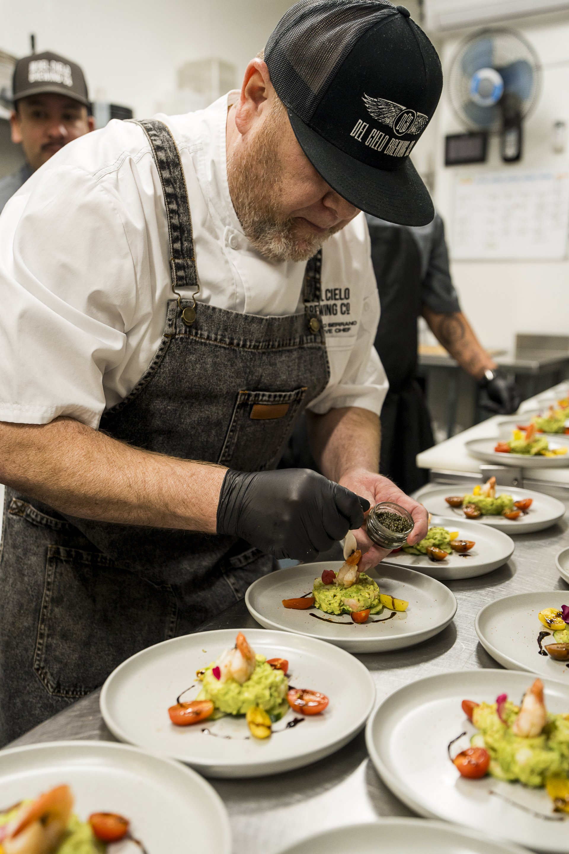 Chef garnishing dishes in a professional kitchen with plated gourmet food.