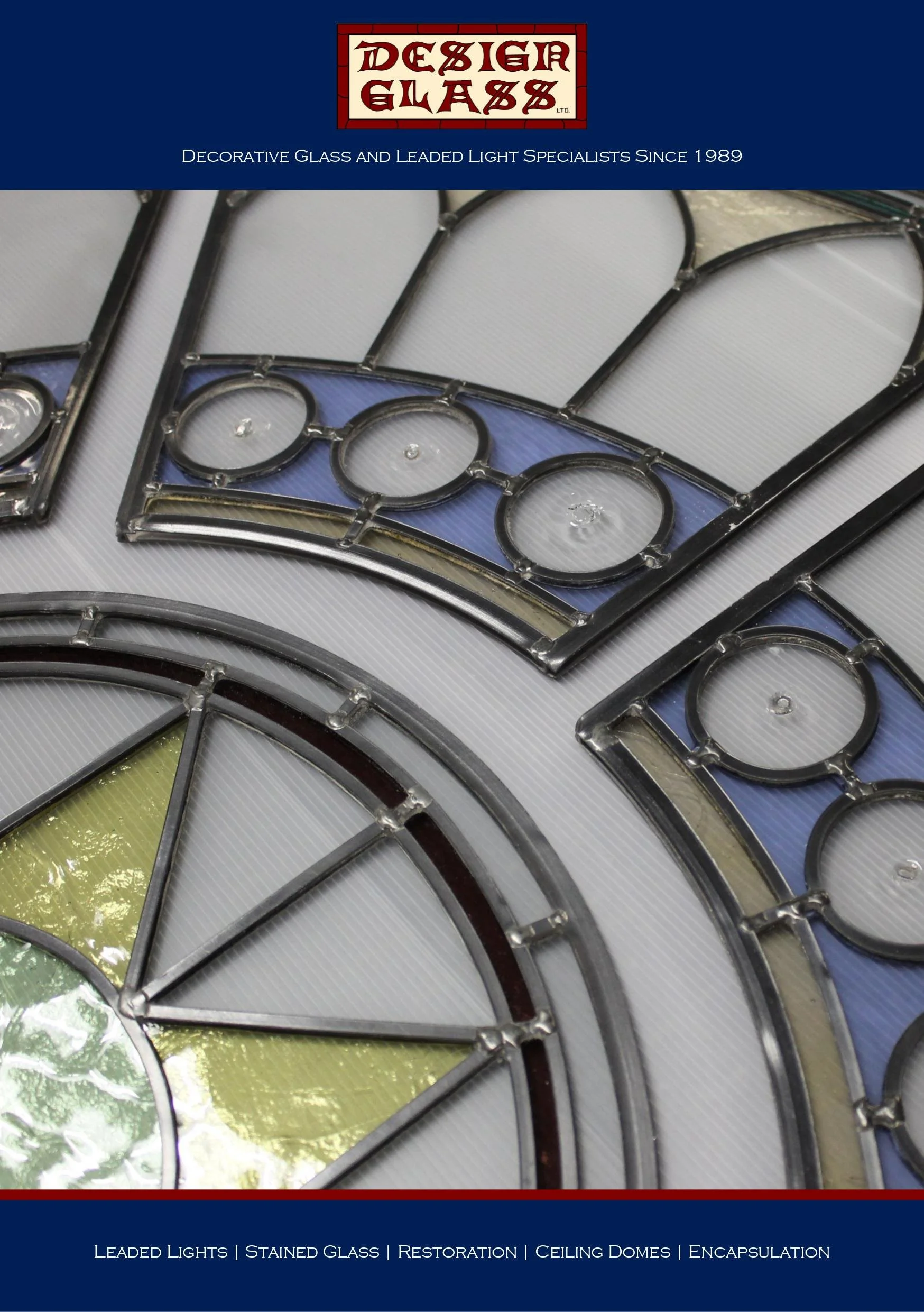 Close-up of stained glass and metal framework with colored glass sections in shades of yellow, blue, green, and brown, part of a decorative stained glass design for a ceiling or window.