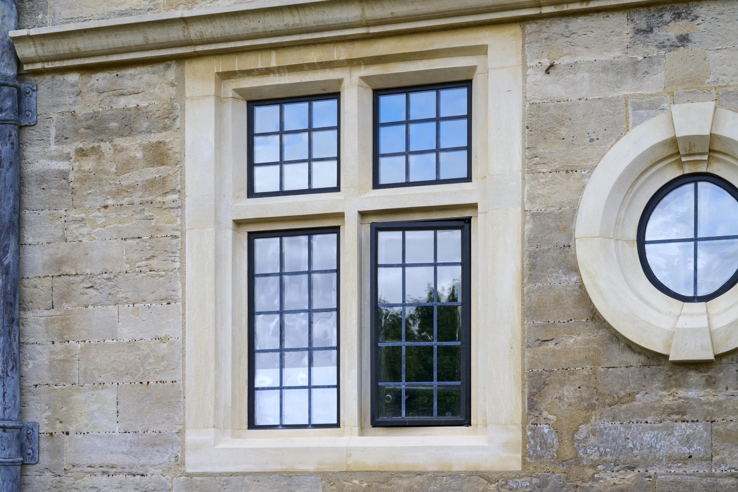 A stone building with four grid-patterned windows and a circular window with a protruding frame.